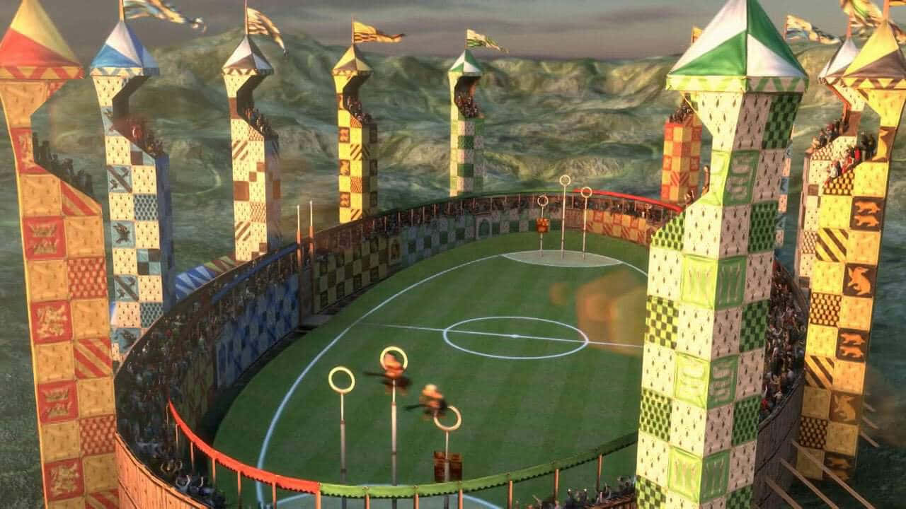 The Hogwarts Quidditch Pitch 桌布 壁紙 — 一個充滿活力的魁地奇球場，設有魔法球門和飛行的球員，背景是山巒。