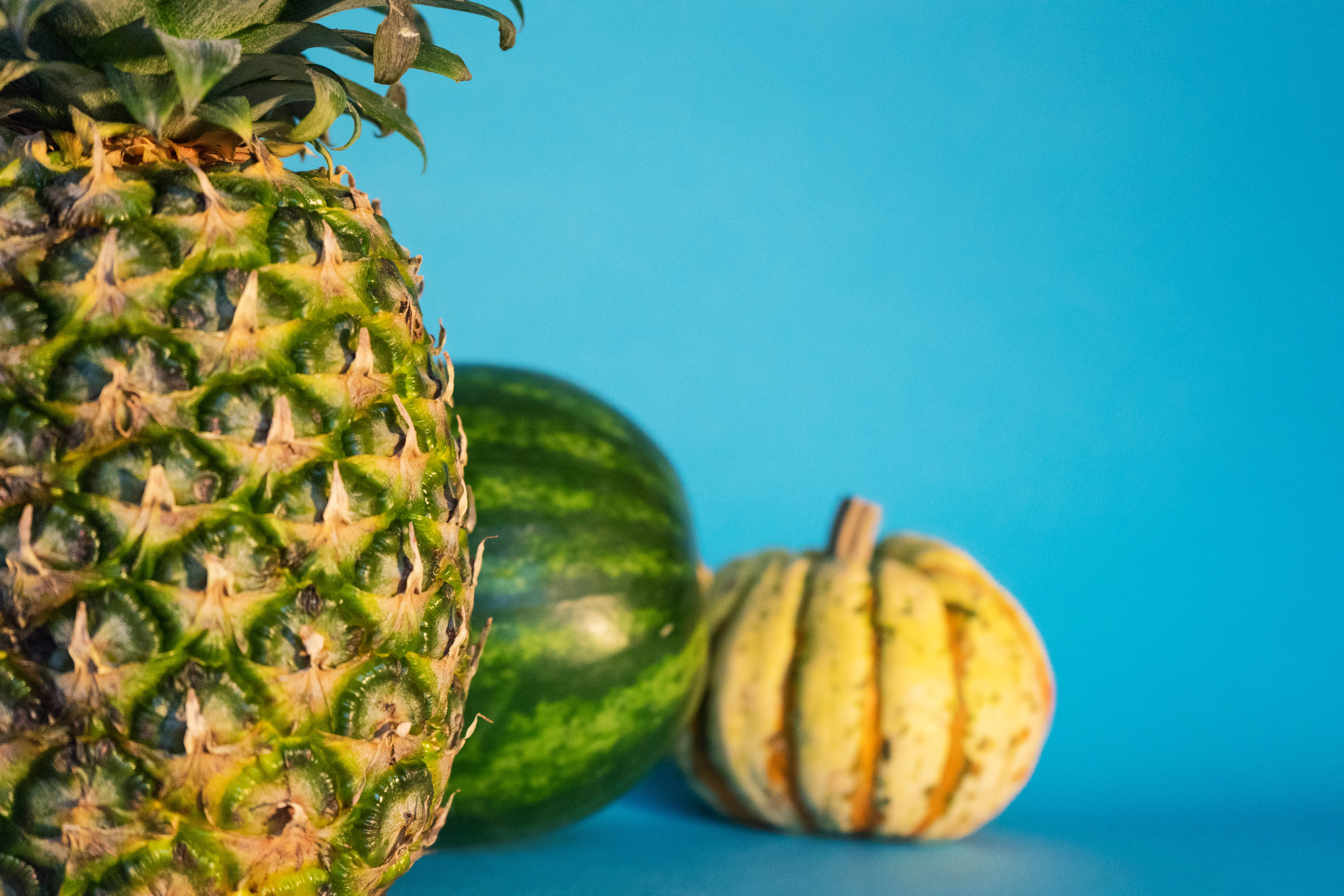 Fruits 桌布 壁紙 — 一個充滿活力的鳳梨西瓜和條紋葫蘆放在純藍色背景上，景深較淺。