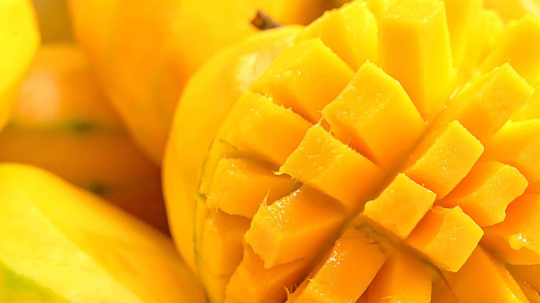 Mango 桌布 壁紙 — 一個充滿活力的黃色芒果的特寫，被切成整齊的方塊，多汁的果肉在明亮的光線下閃閃發光。