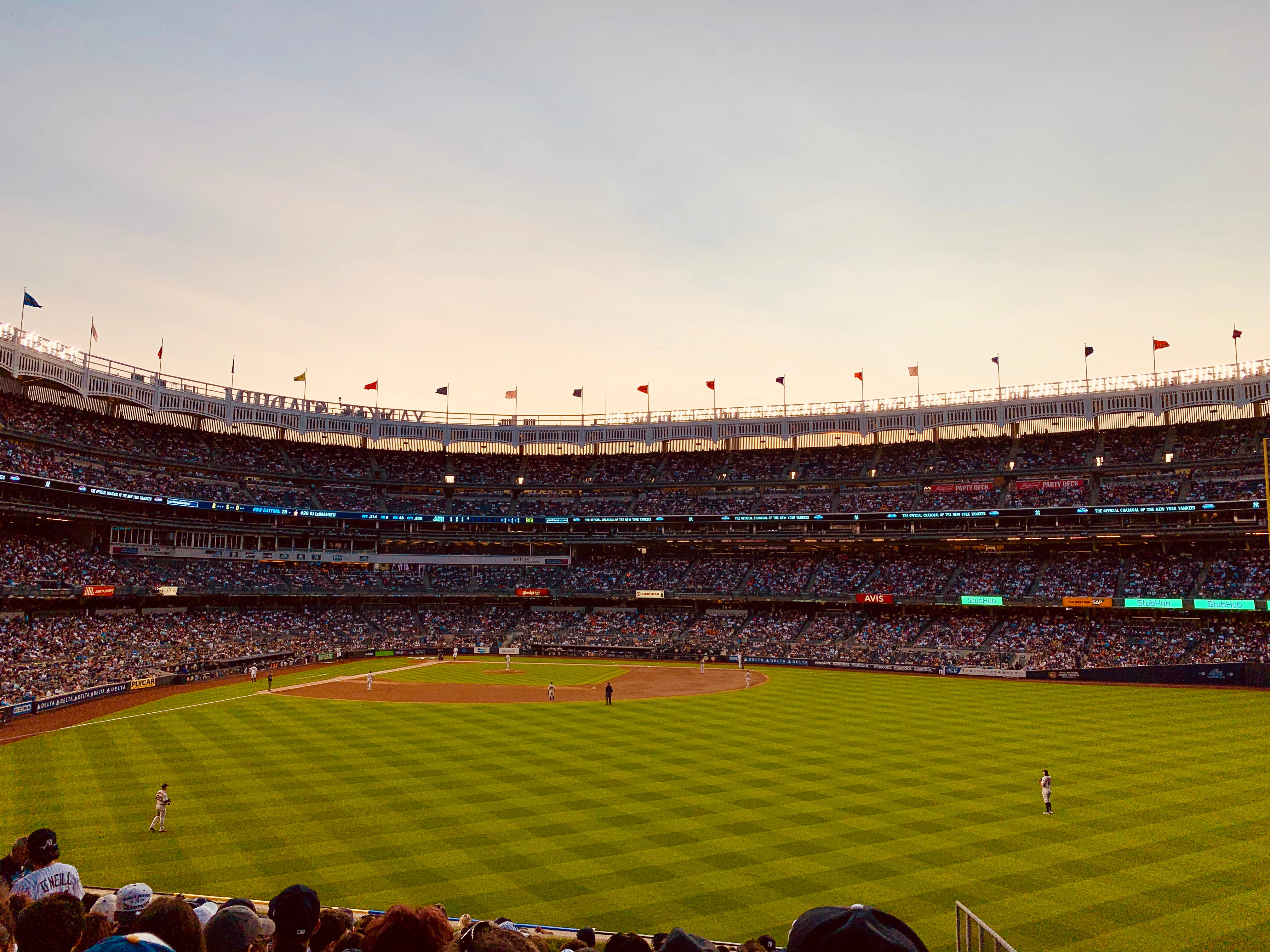 MLB 桌布 壁紙 — 一個充滿觀眾的棒球場，在柔和的金色日落天空下。