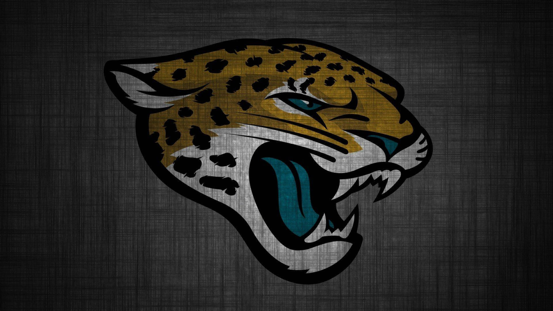 Jaguars 桌布 壁紙 — 一個兇猛咆哮的美洲豹標誌，帶有黃色斑點皮毛和藍綠色眼睛，置於深色紋理灰色背景上。