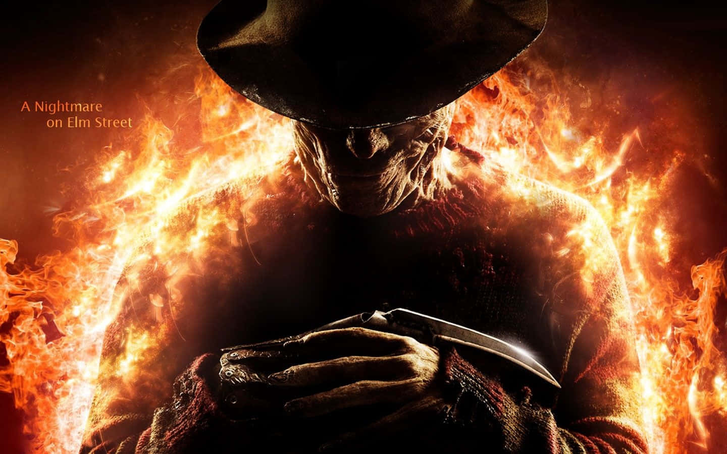 Freddy Krueger 桌布 壁紙 — 一個兇猛的佛萊迪·克魯格從咆哮的火焰中出現，手持刀刃，處於熾熱的噩夢場景中。