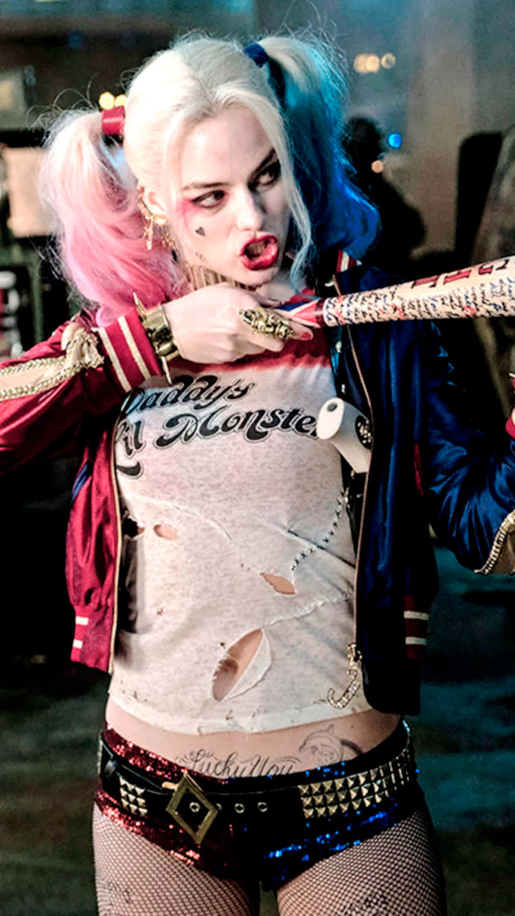 Margot Robbie Harley Quinn 桌布 壁紙 — 一個兇猛的哈莉·奎茵，紮著粉紅色和藍色的雙馬尾，在 gritty 的城市環境中揮舞著棒球棍。