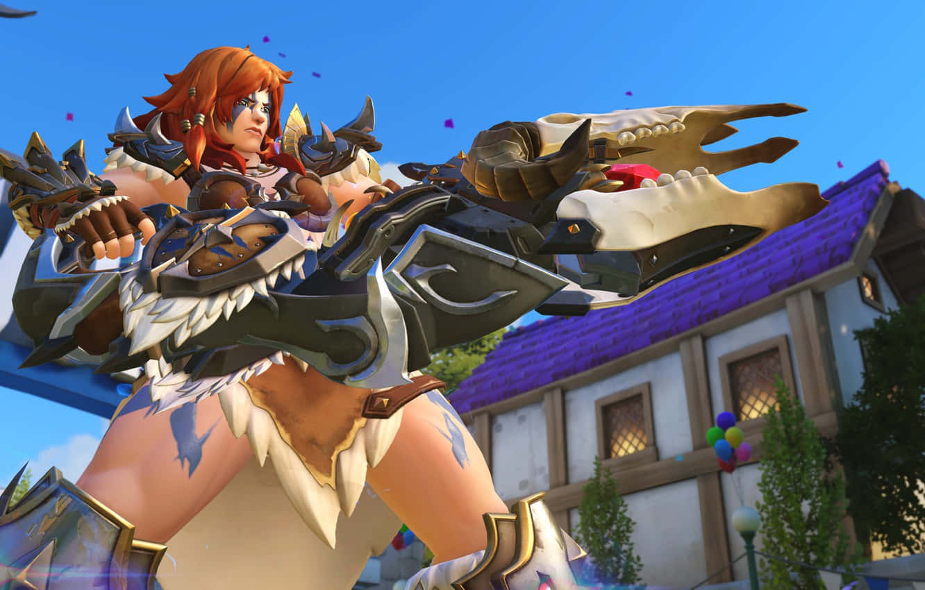 Overwatch Zarya 桌布 壁紙 — 一個兇猛的紅髮戰士身穿華麗盔甲，在色彩繽紛的村莊上空，對著明亮的藍天揮舞著巨大的龍頭骨武器。