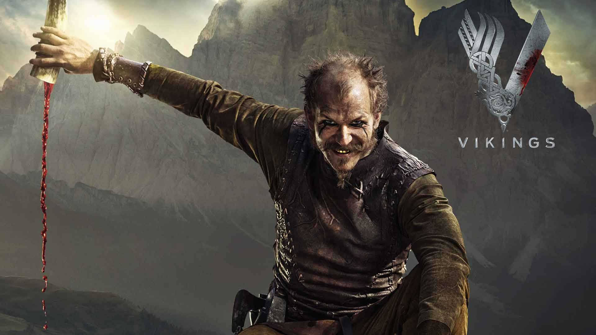 Vikings 桌布 壁紙 — 一個兇猛的維京戰士手持血跡斑斑的斧頭，在戲劇性的天空下，以崎嶇的山脈為背景，勝利地站立著。