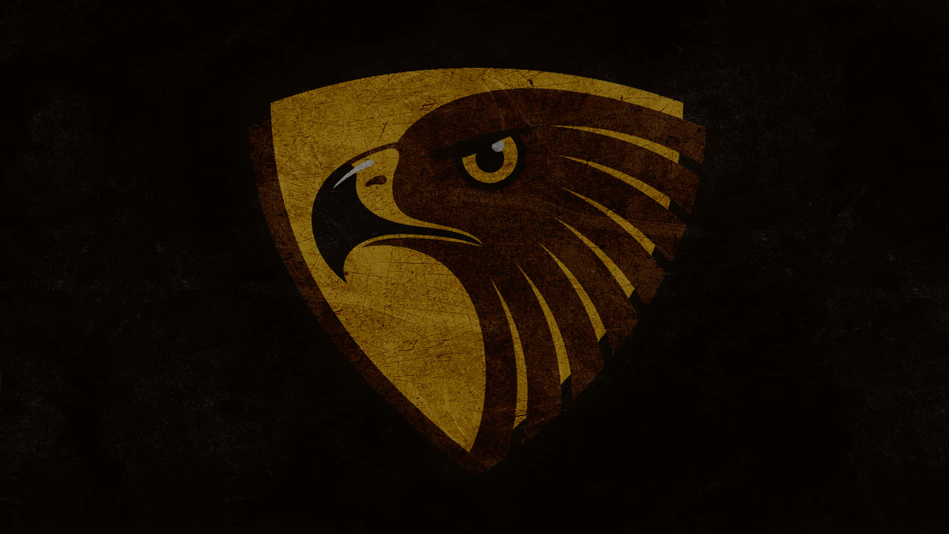 Eagles 桌布 壁紙 — 一個兇猛的金色鷹頭標誌，帶有風化紋理，居中放置在黑暗粗糙的背景上。