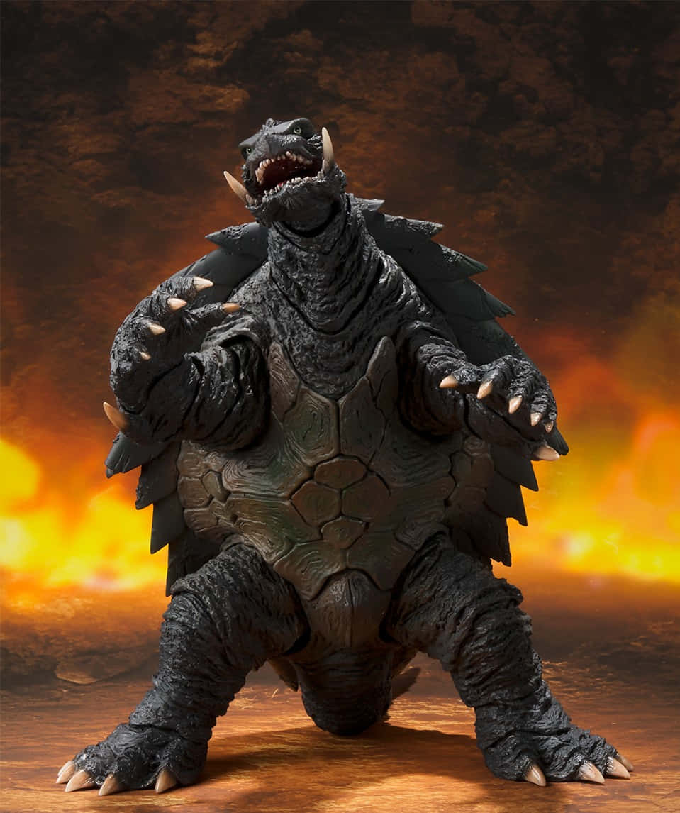 Gamera 桌布 壁紙 — 一個兇猛的黑色的哥吉拉模型在熾熱的橙色和棕色背景下咆哮。