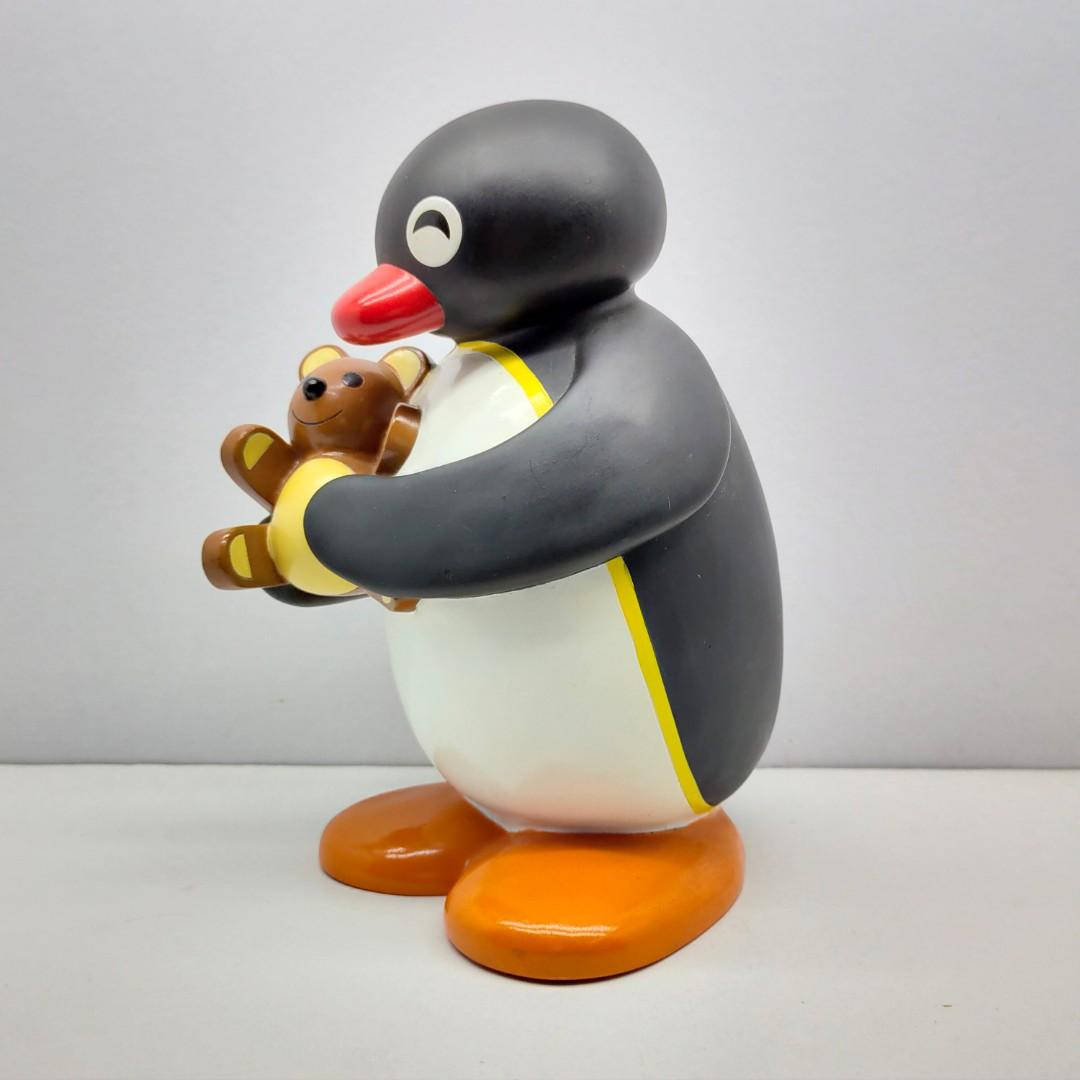 Pingu 桌布 壁紙 — 一個光滑的塑膠企鵝公仔在純白色背景前抱著一隻小棕色泰迪熊。