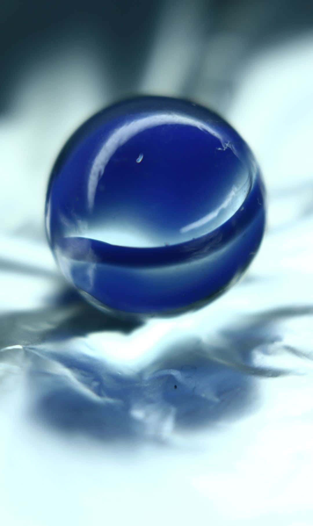 1080x1812 桌布 壁紙 — 一個光滑的深藍色球體放置在反光表面上，帶有柔和的光線和模糊的背景。