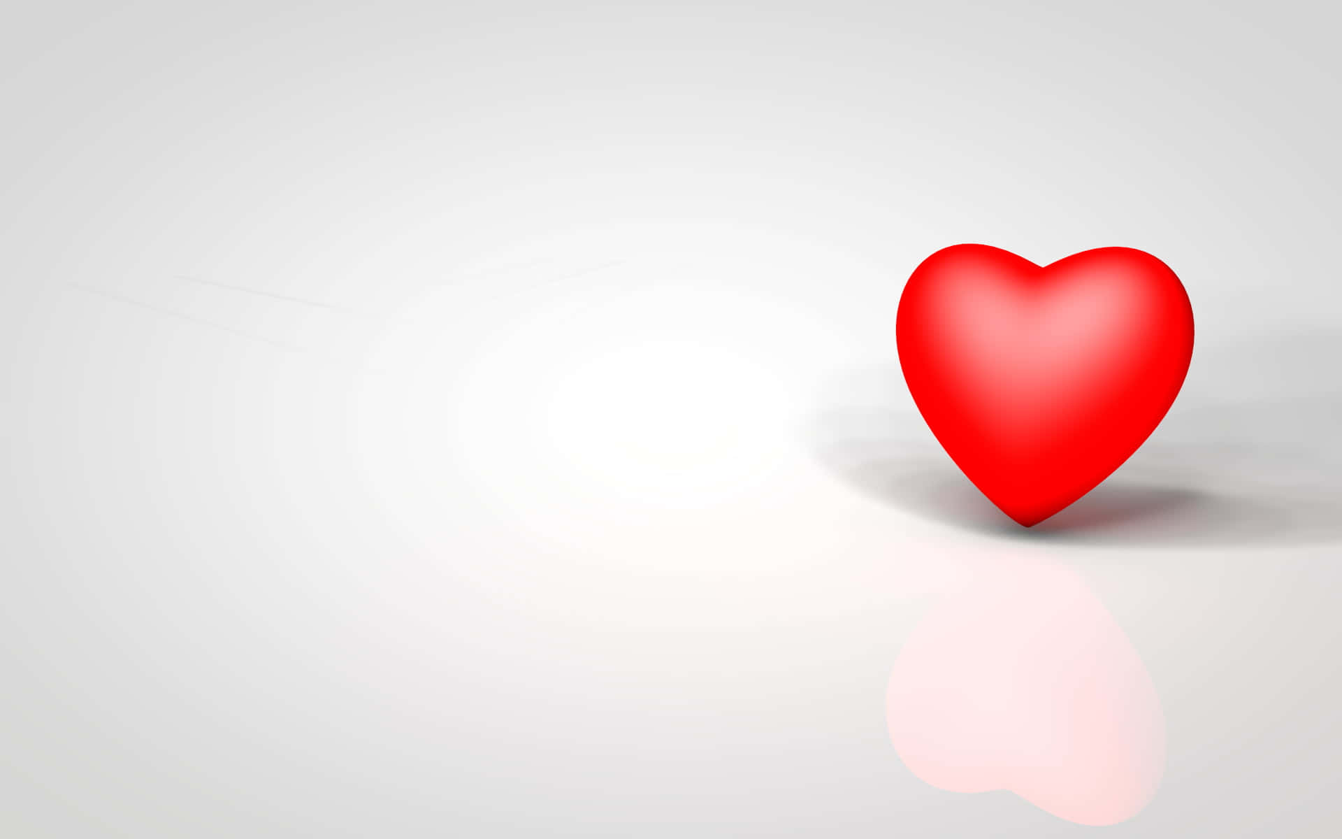 Cartoon Heart 桌布 壁紙 — 一個光滑的紅色心形放在極簡的白色表面上，投射出柔和的反射和陰影。