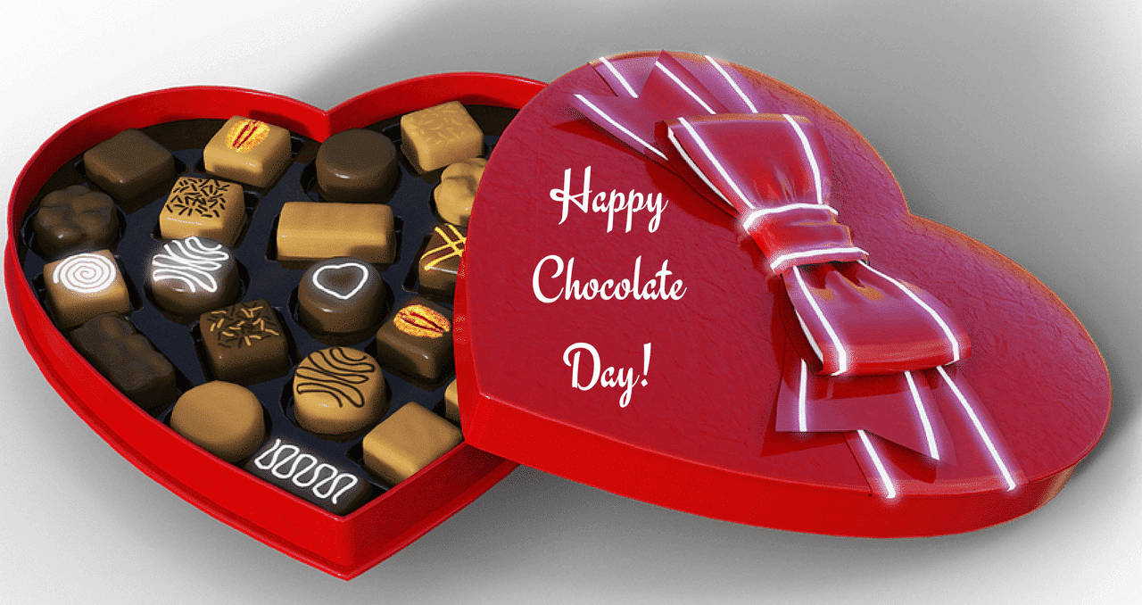 Chocolate Day 桌布 壁紙 — 一個光滑的紅色心形盒子，裝滿各種巧克力，頂部有蝴蝶結和Happy Chocolate Day訊息。