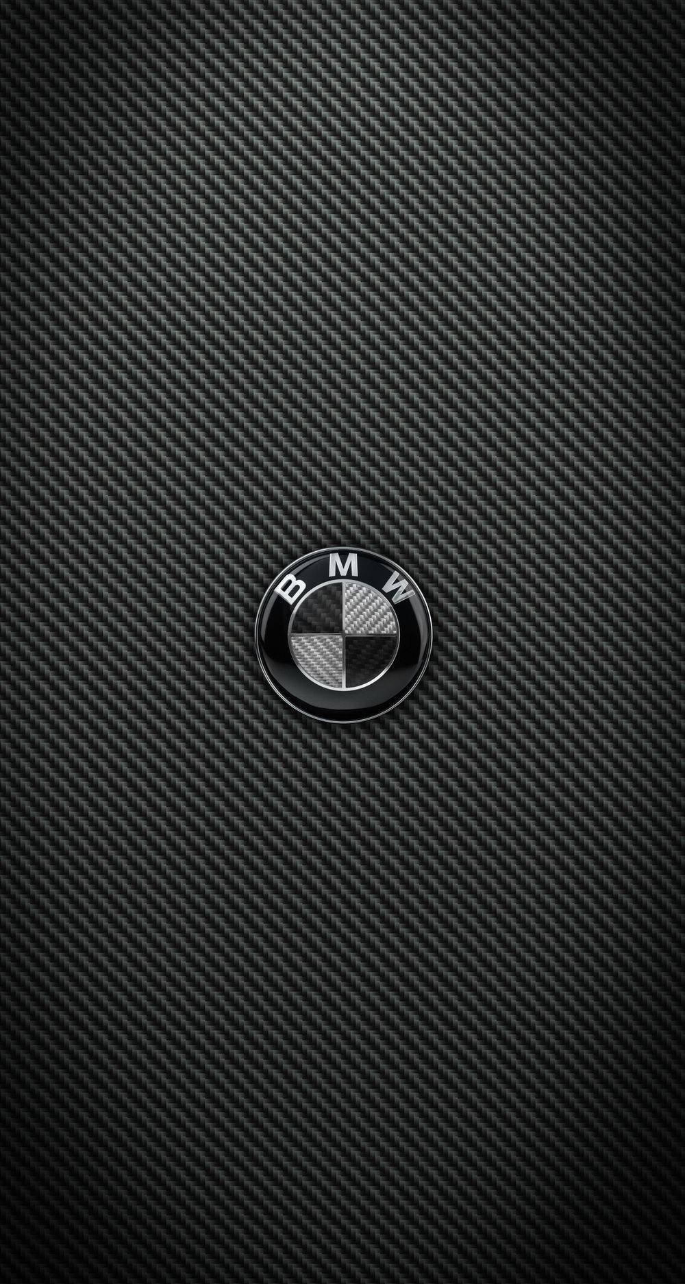 Carbon 桌布 壁紙 — 一個光澤的BMW標誌居中在紋理黑色碳纖維背景上。
