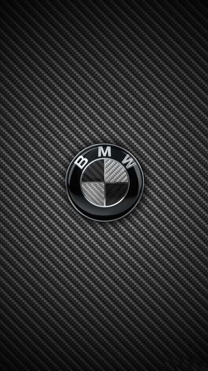 Bmw Android 桌布 壁紙 — 一個光澤的BMW標誌置於帶有斜紋編織圖案的紋理黑色碳纖維背景中央。