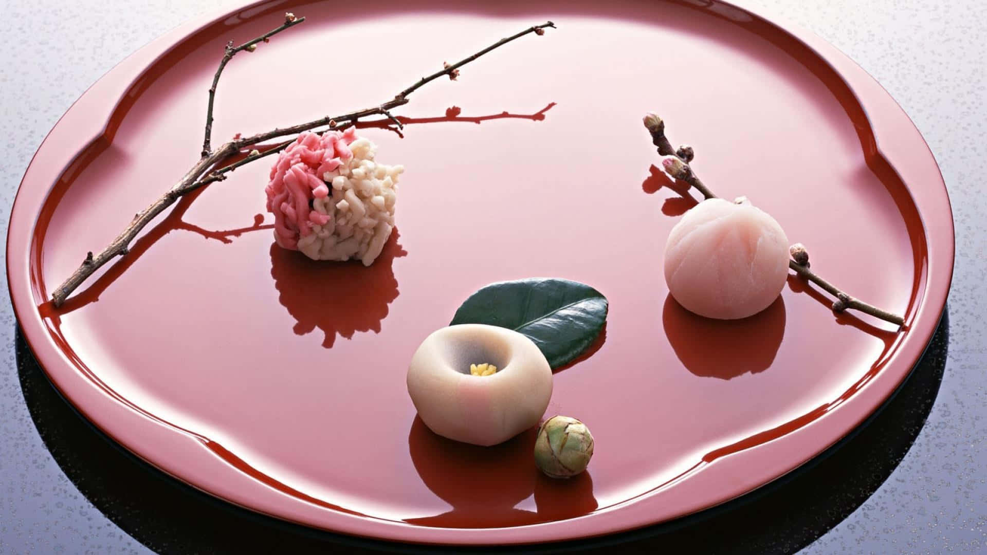 Delicious Food 桌布 壁紙 — 一個光澤的粉紅色漆器托盤上，擺放著精緻的日本甜點和櫻花枝，以極簡優雅的方式排列。
