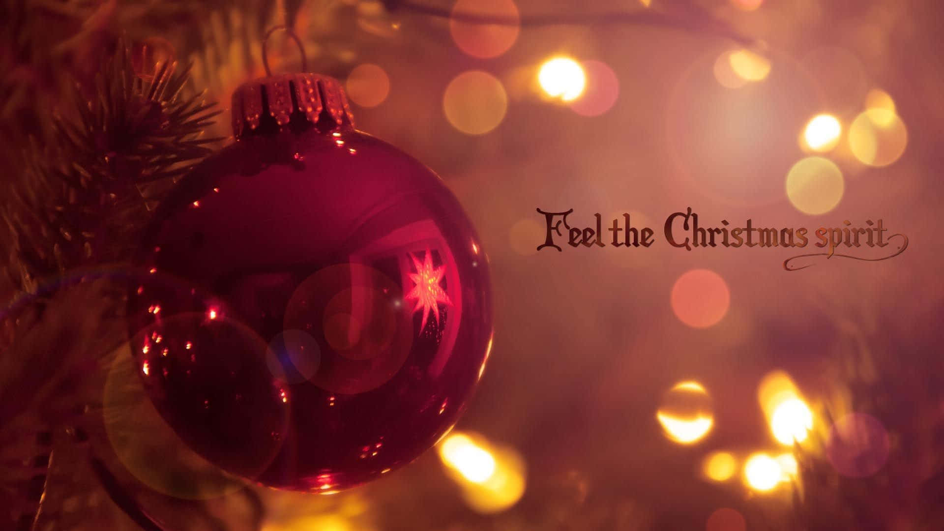 Tumblr Christmas 桌布 壁紙 — 一個光澤的紅色聖誕裝飾掛在松針和溫暖發光的燈光中，文字為 Feel the Christmas spirit。