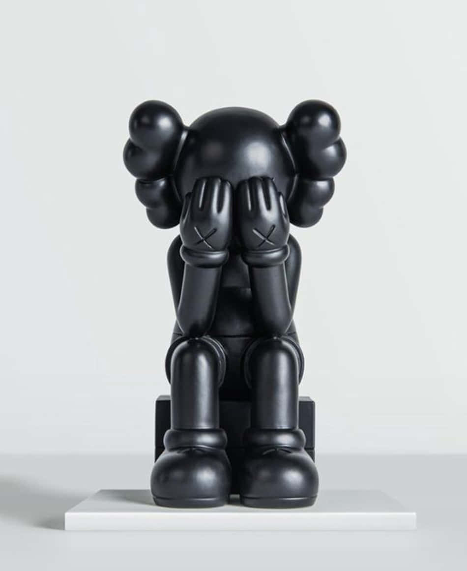 桌布 壁紙 — 一個光澤的黑色KAWS Companion雕塑坐在白色底座上，用帶有X標記的手遮住眼睛。