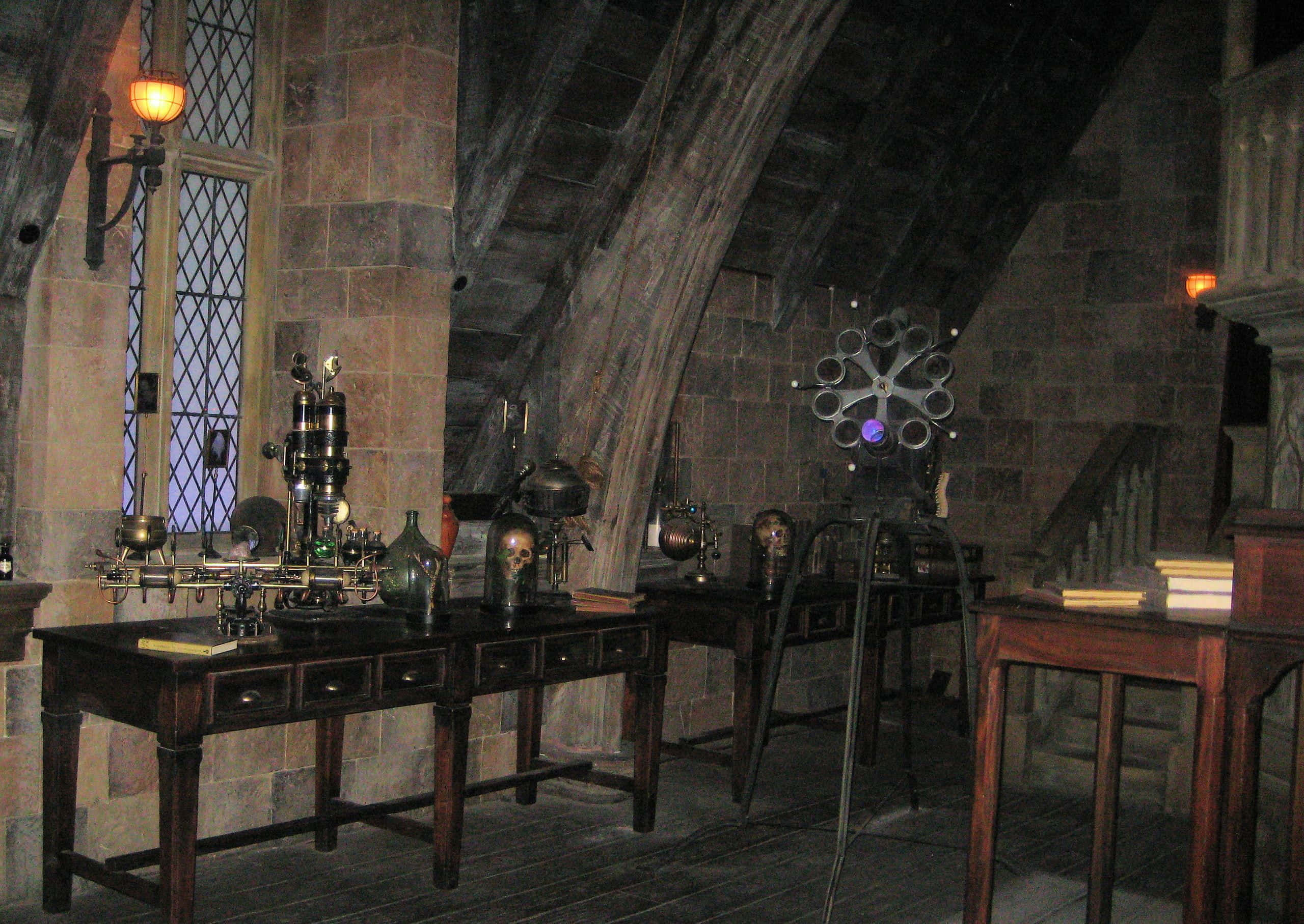 The Hogwarts Potions Class 桌布 壁紙 — 一個光線昏暗的中世紀石室，木桌上放著神秘科學儀器和頭骨，在溫暖的燈光下。