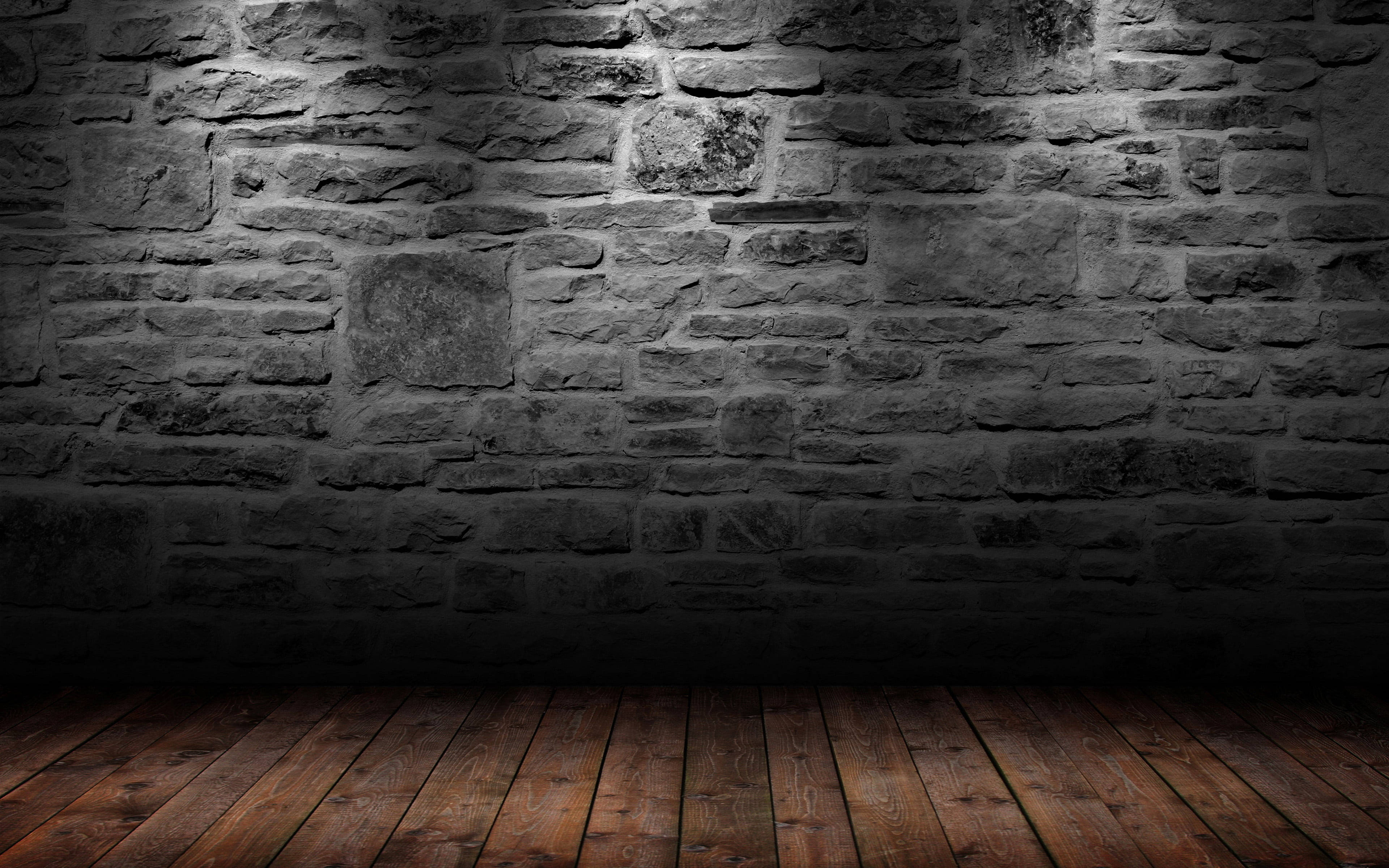 Stone Wall 桌布 壁紙 — 一個光線昏暗的房間，有粗糙的石牆和木地板，由聚焦的聚光燈照亮。