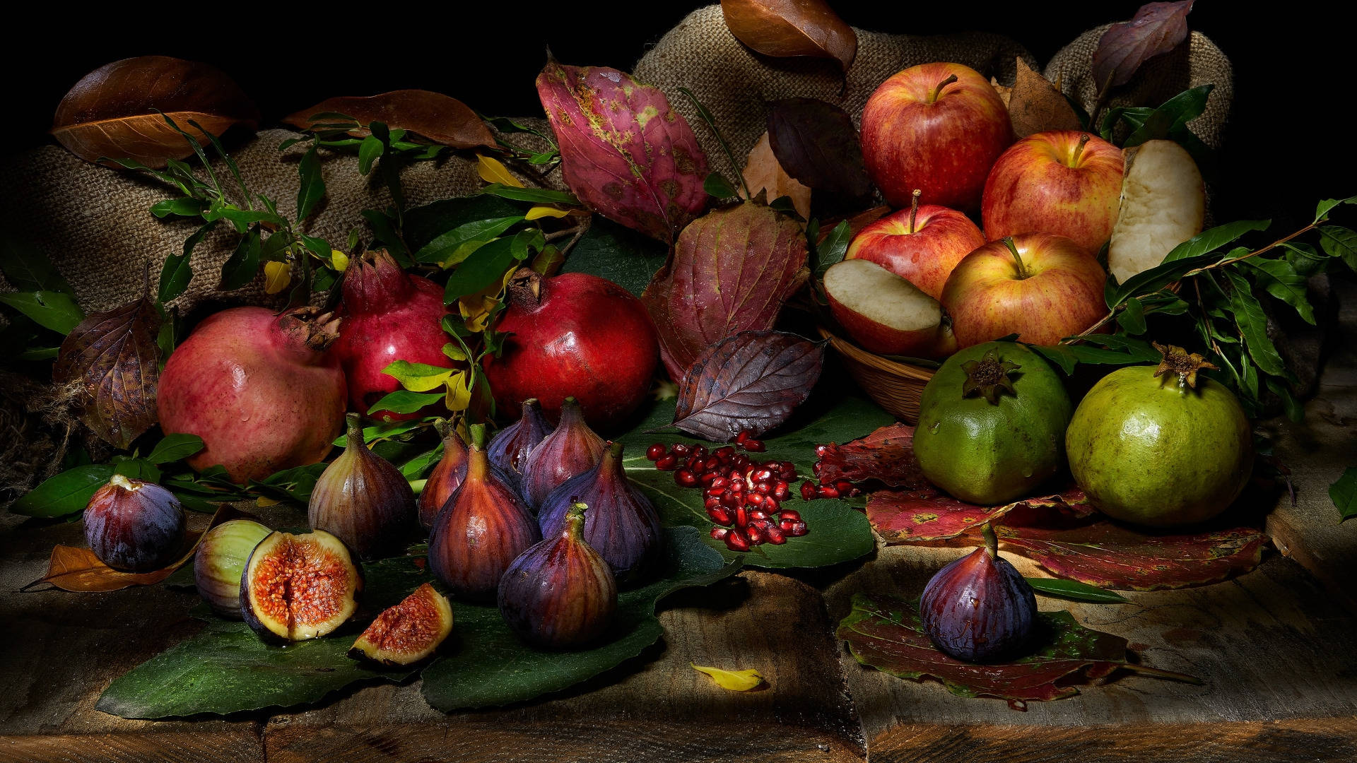 Fruits And Vegetables 桌布 壁紙 — 一個光線豐富的靜物，石榴、無花果、蘋果和樹葉擺放在質樸的木質表面上。