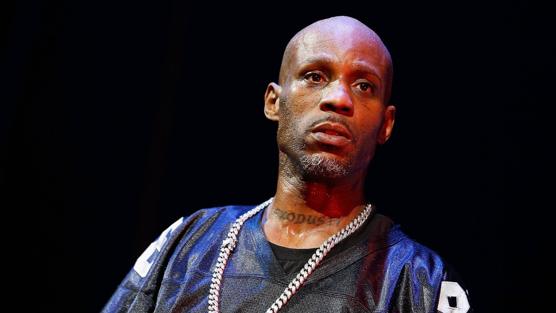 Dmx 桌布 壁紙 — 一個光頭、留山羊鬍、戴粗鏈條項鍊的男人，在黑色背景下強烈凝視。
