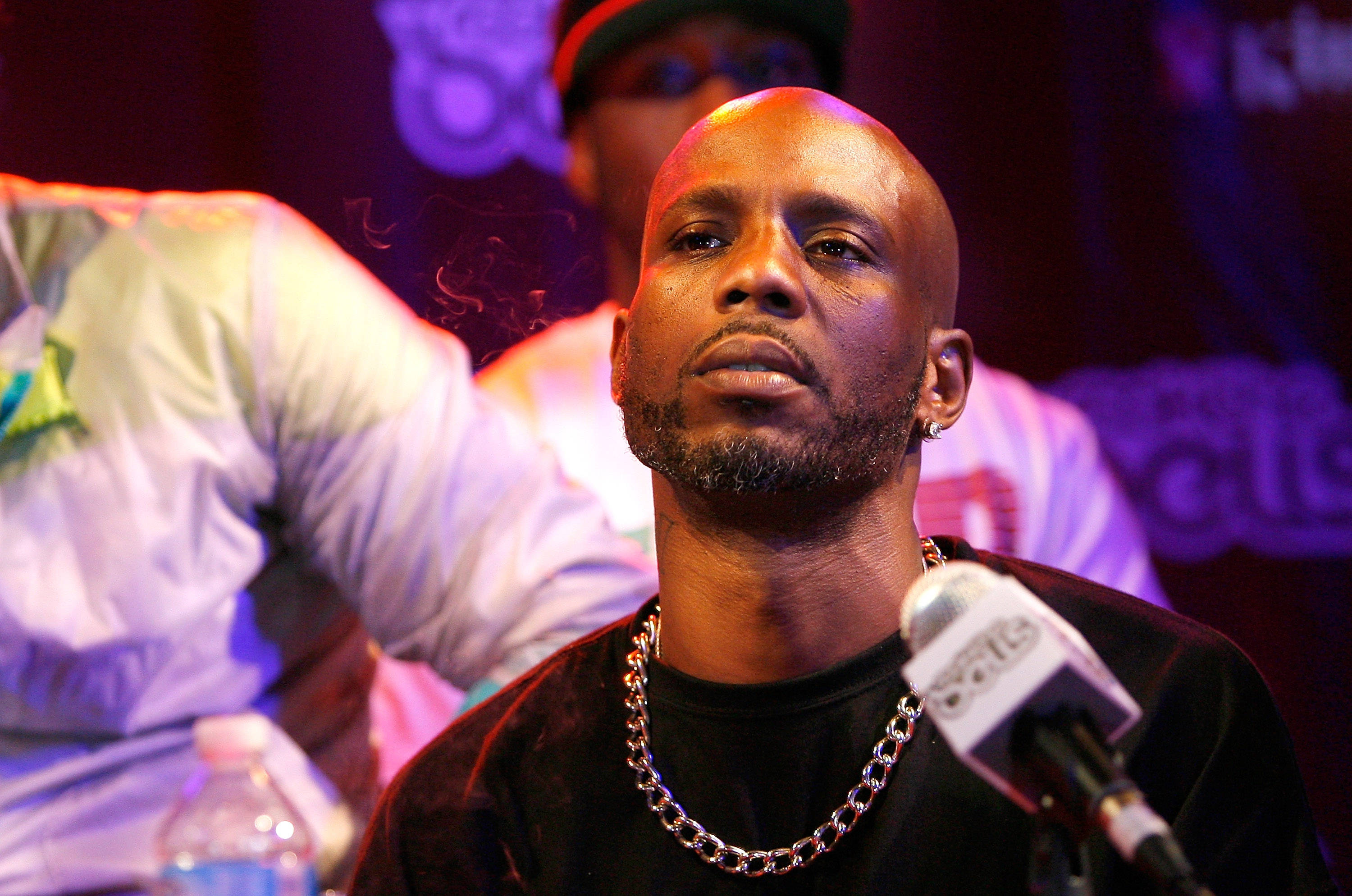 Dmx 桌布 壁紙 — 一個光頭、留山羊鬍、戴鏈條項鍊的男人在色彩繽紛的舞台燈光下對著麥克風說話。