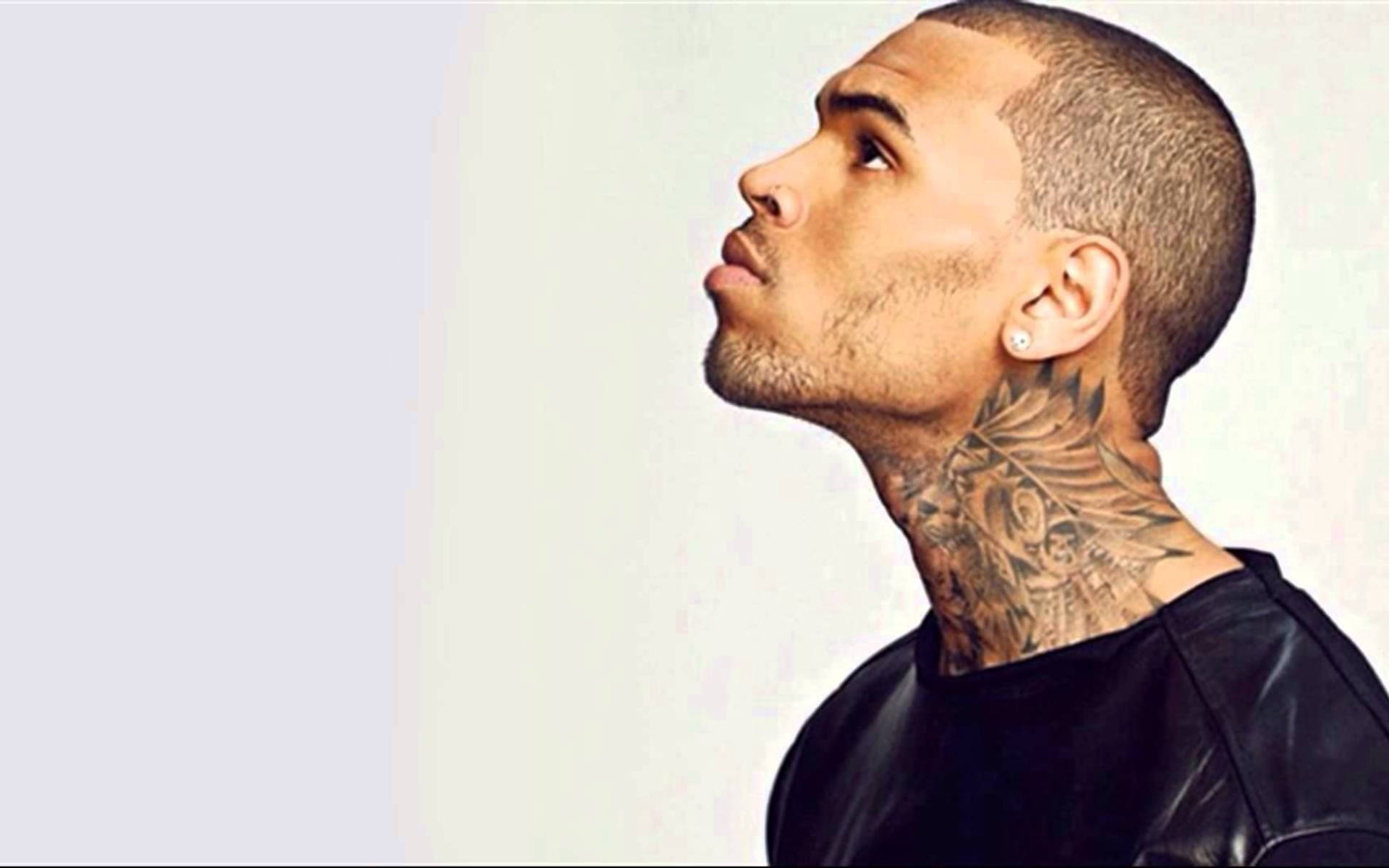 Chris Brown 桌布 壁紙 — 一個光頭且頸部有刺青的男人在純色淺色背景下向上凝視。