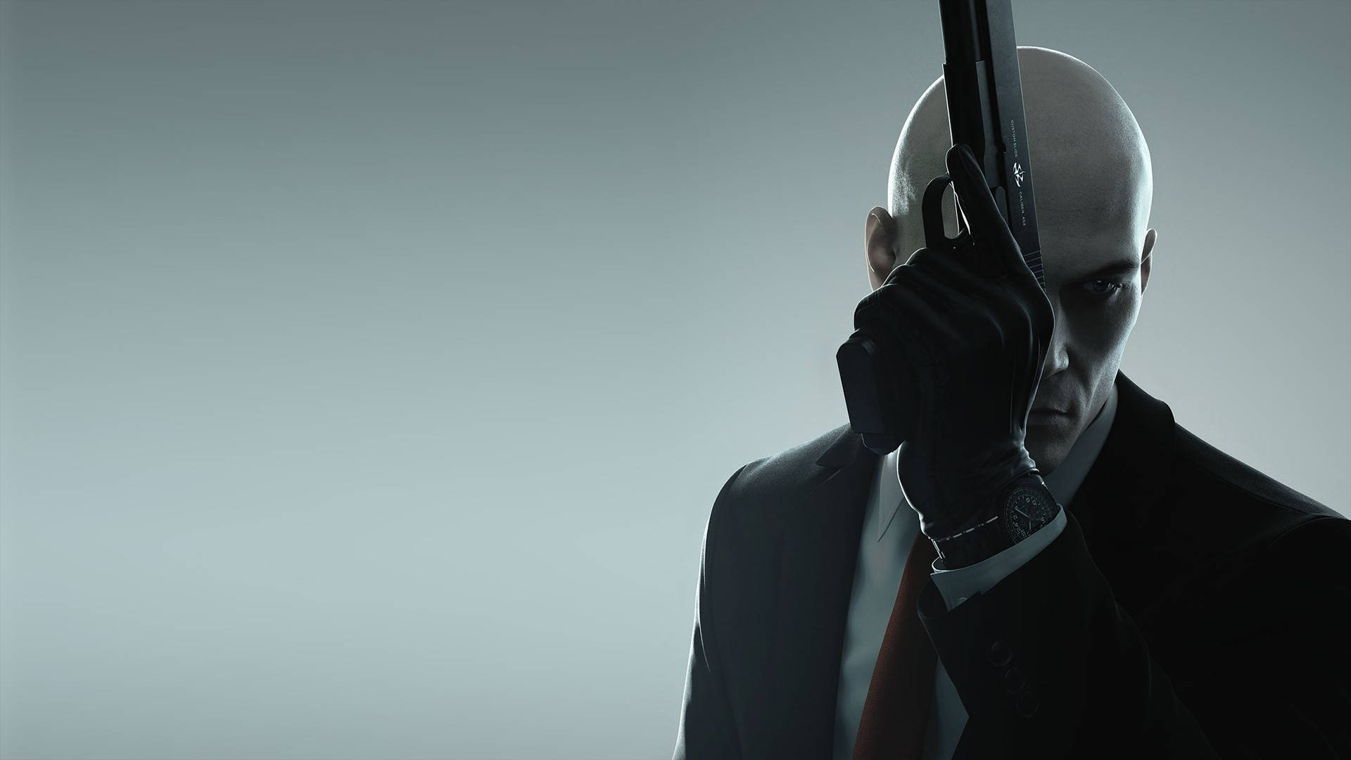 hitman absolution HD 桌布 壁紙 — 一個光頭刺客穿著深色西裝，在柔和的灰色背景前將手槍抵住自己的太陽穴。