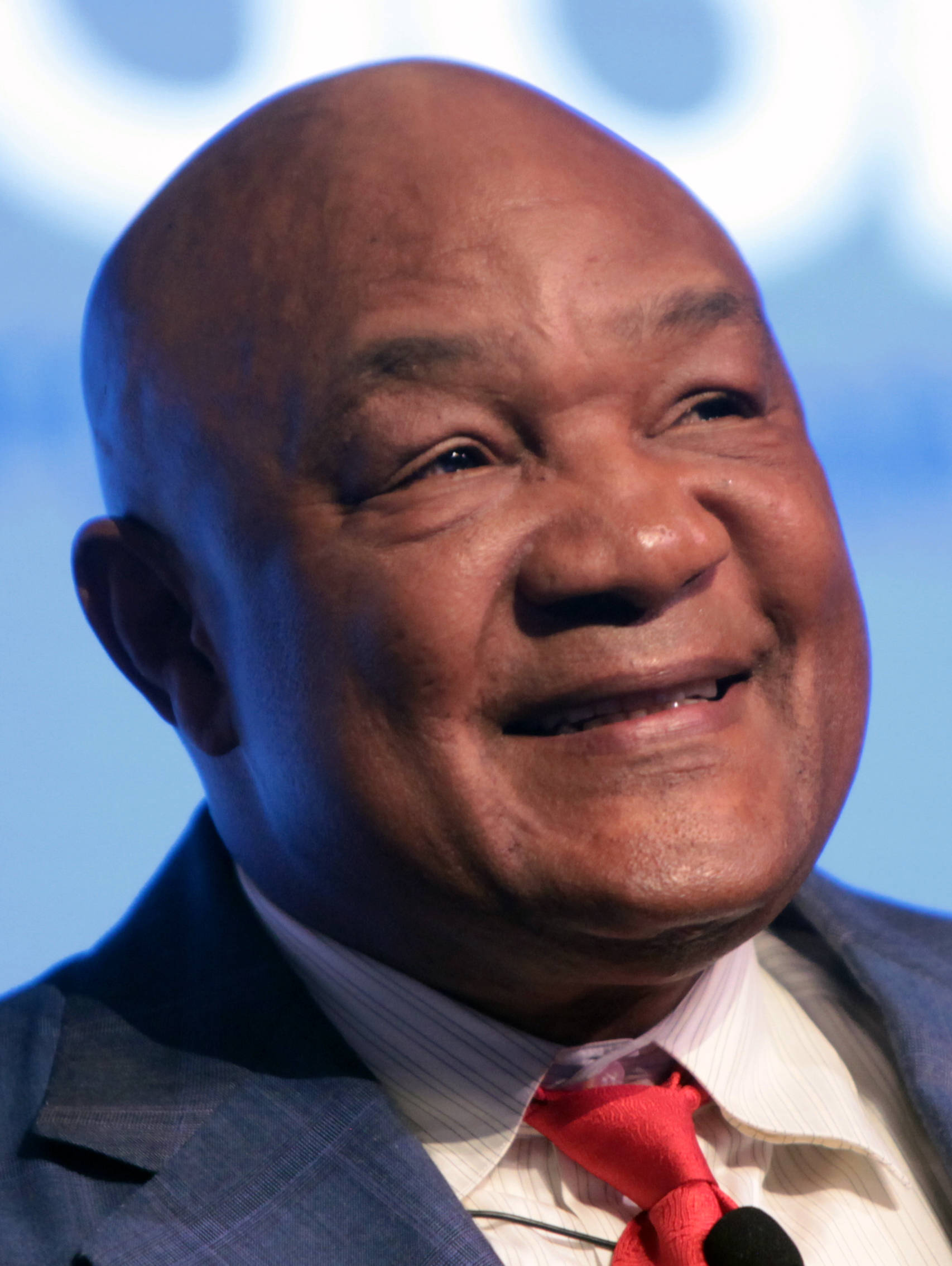 Smile 桌布 壁紙 — 一個光頭男人穿著西裝和紅色領帶，在藍色背景前溫暖微笑的特寫肖像。