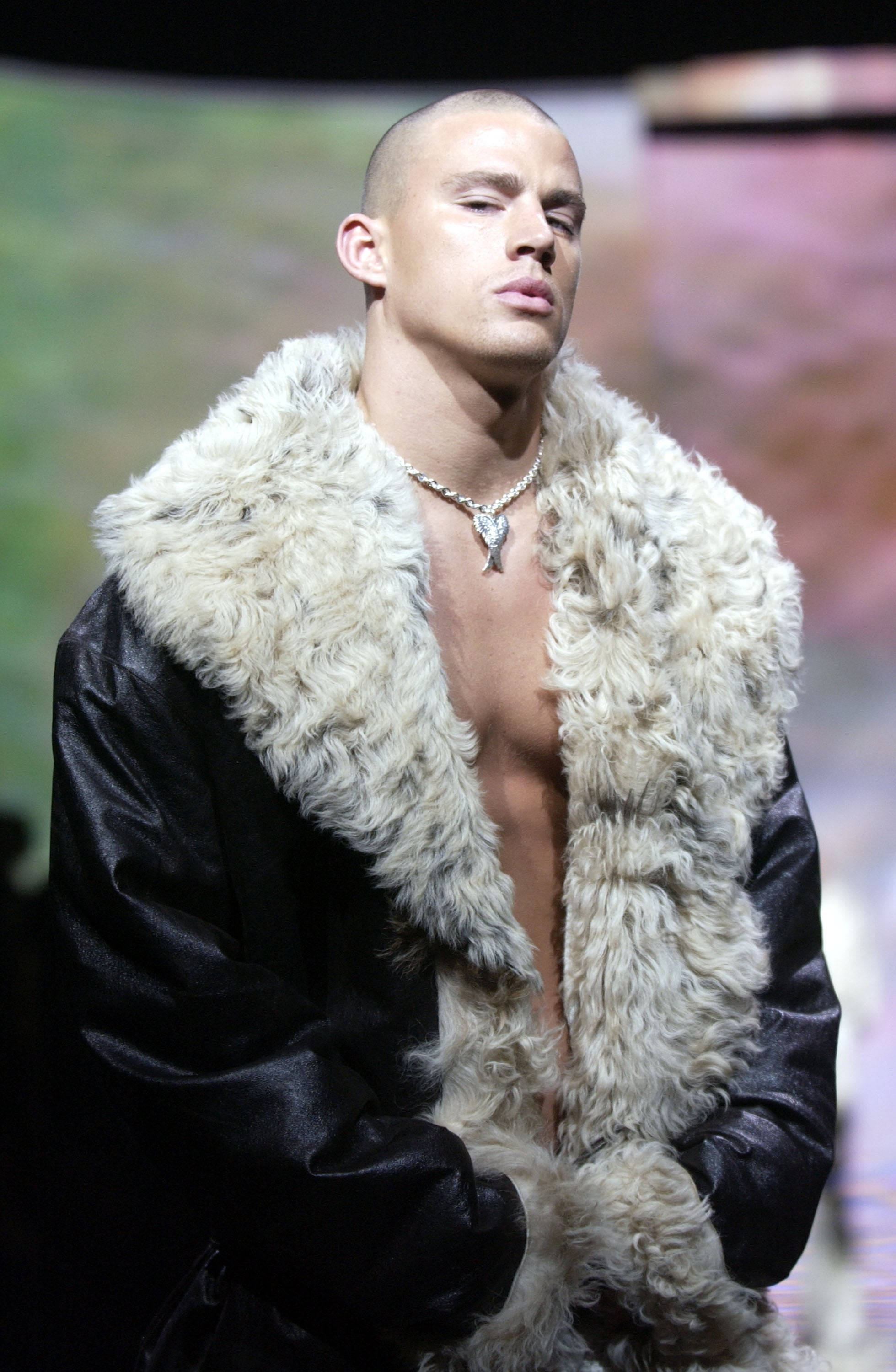 Channing 桌布 壁紙 — 一個光頭男人穿著黑色皮夾克，搭配白色蓬鬆毛領，在明亮燈光下自信地站在伸展台上。
