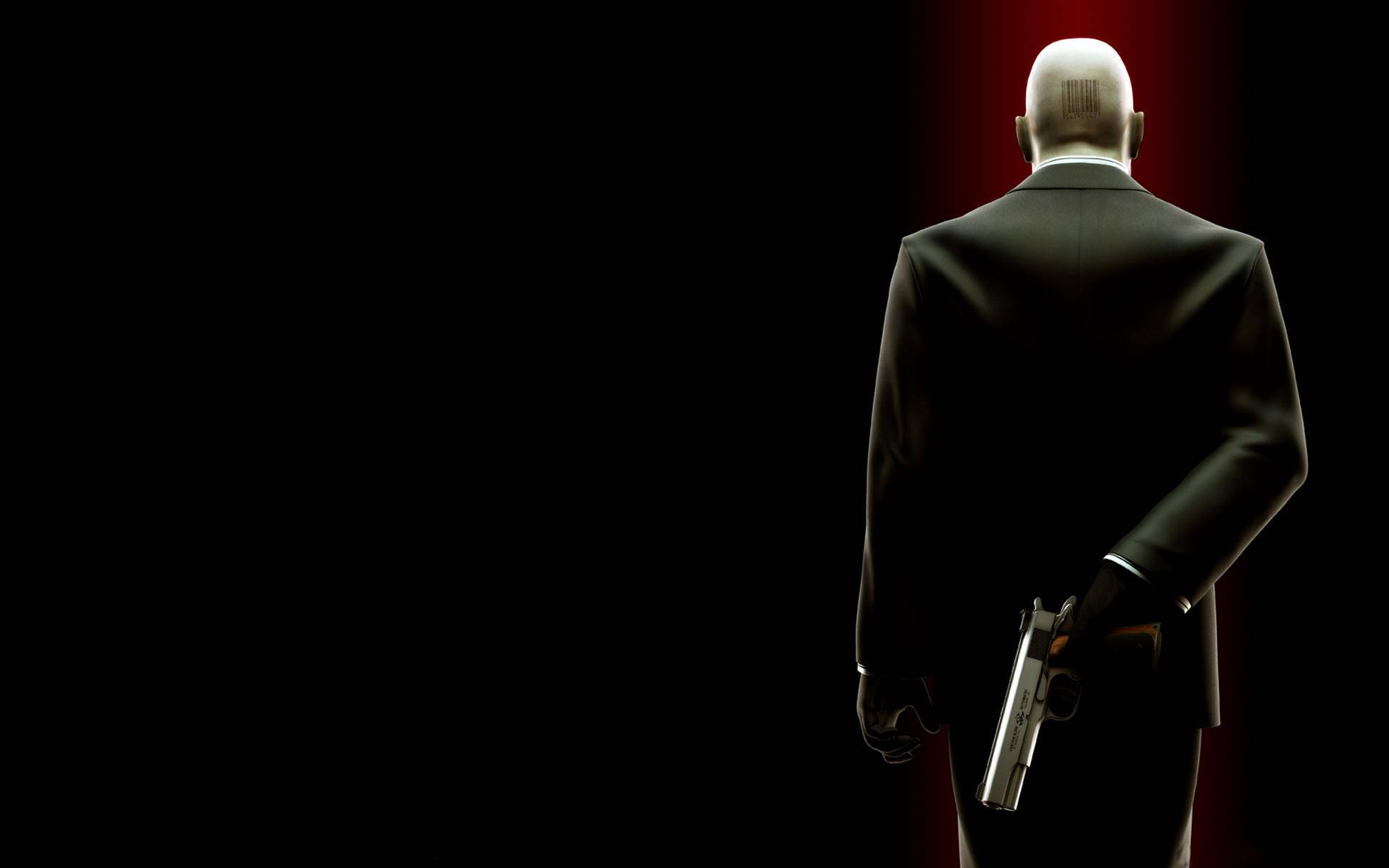 hitman absolution HD 桌布 壁紙 — 一個光頭男人穿著黑色西裝，背對觀眾，在黑暗背景下的紅色聚光燈下拿著槍。