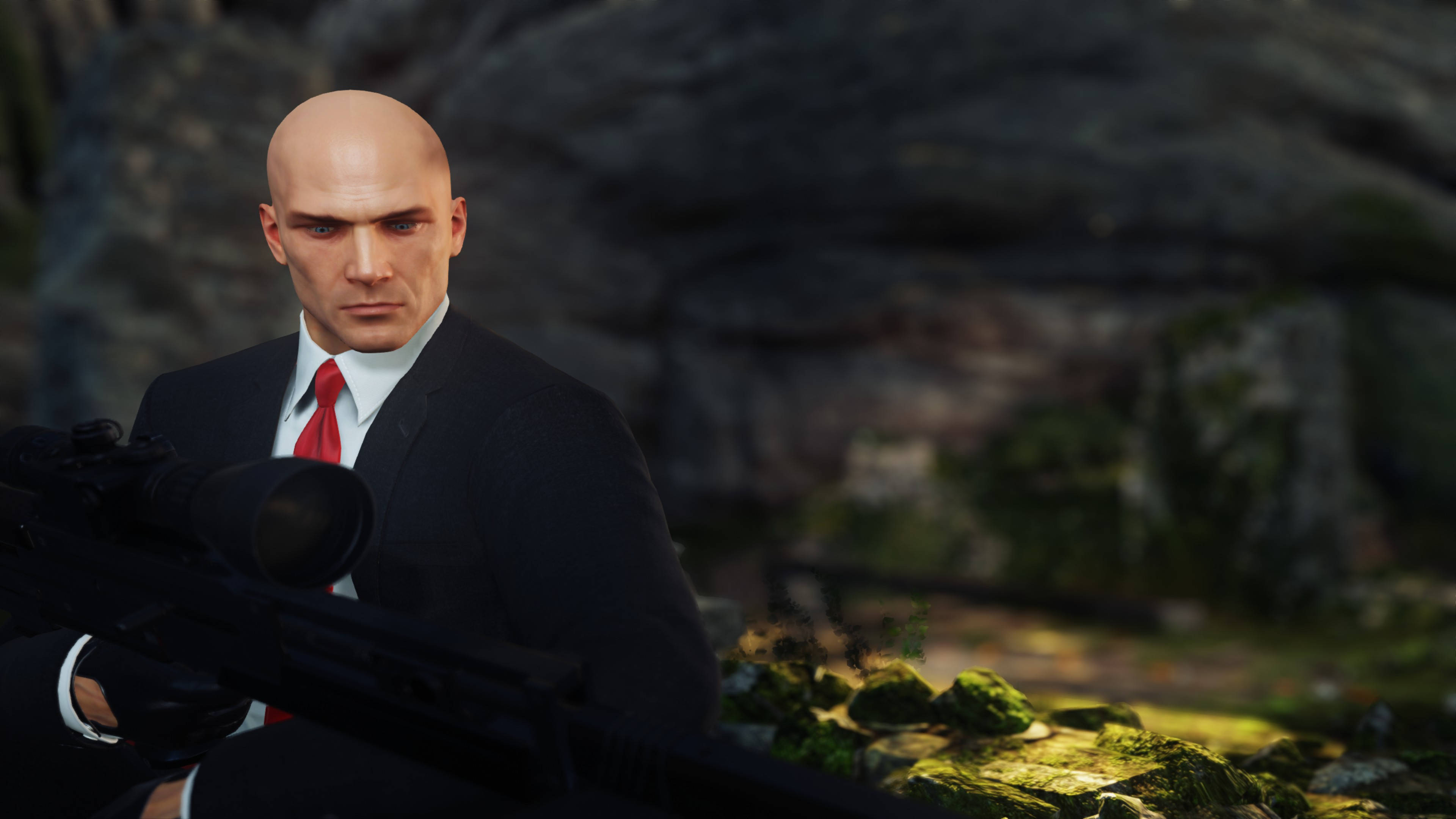hitman iPhone 桌布 壁紙 — 一個光頭男人穿著黑色西裝和紅色領帶，在長滿苔蘚的岩石背景下拿著狙擊步槍。