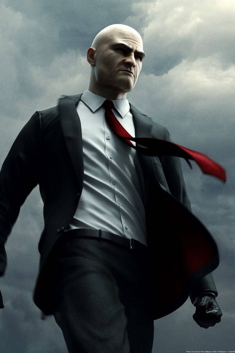 hitman iPhone 桌布 壁紙 — 一個光頭男人穿著黑色西裝和紅色領帶，帶著強烈的表情在暴風雨的灰色天空下大步向前。