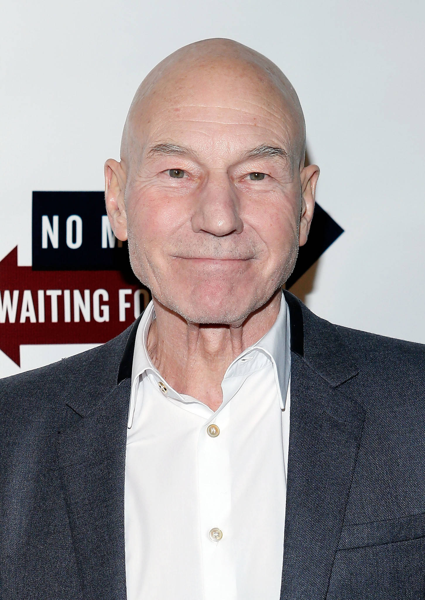 Celebrity 桌布 壁紙 — 一個光頭男士穿著深色西裝和白色襯衫，微笑面對鏡頭的近距離肖像。