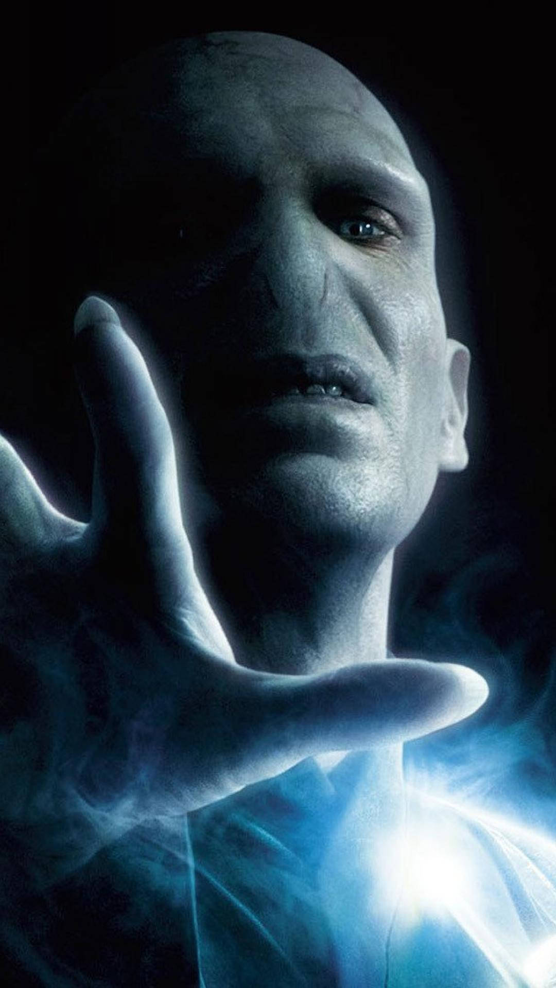 voldemort 桌布 壁紙 — 一個光頭男子在黑暗背景下，從他伸出的手中散發出藍色發光能量。