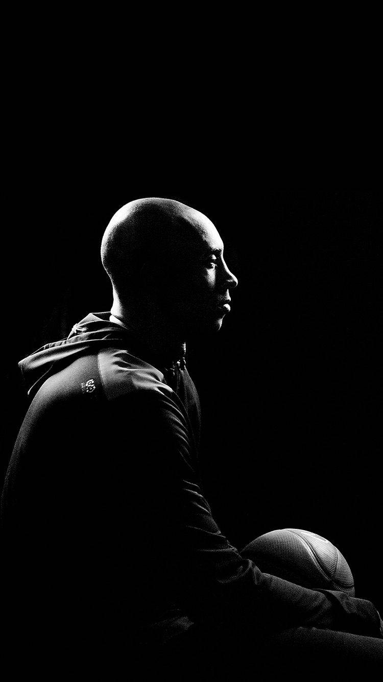 Kobe Bryant iPhone 桌布 壁紙 — 一個光頭男子的剪影，在純黑背景中手持籃球，帶有戲劇性的側光。