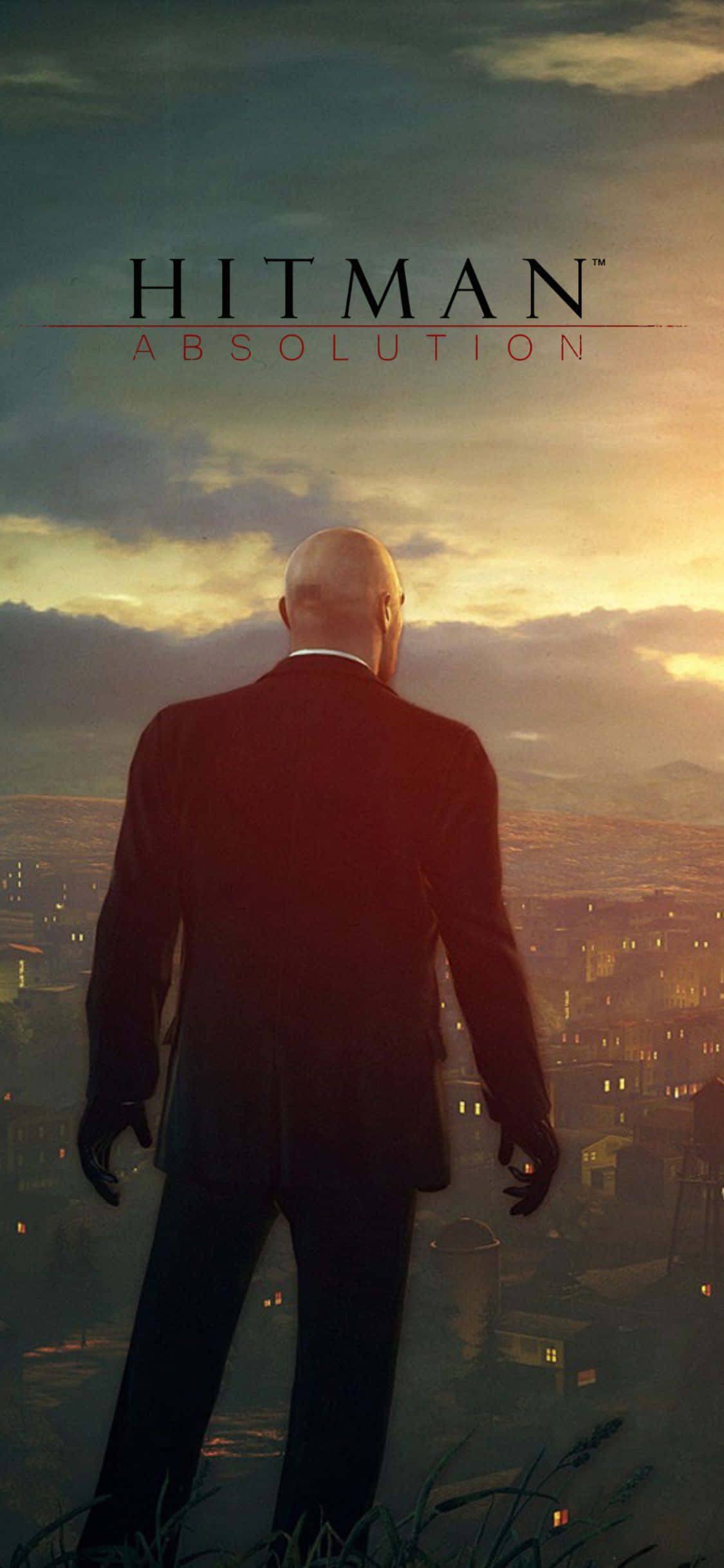 iPhone X Hitman Absolution 桌布 壁紙 — 一個光頭男子穿著深色西裝，在日落時分俯瞰著一座廣闊的城市，溫暖的金色光芒投下長長的影子。