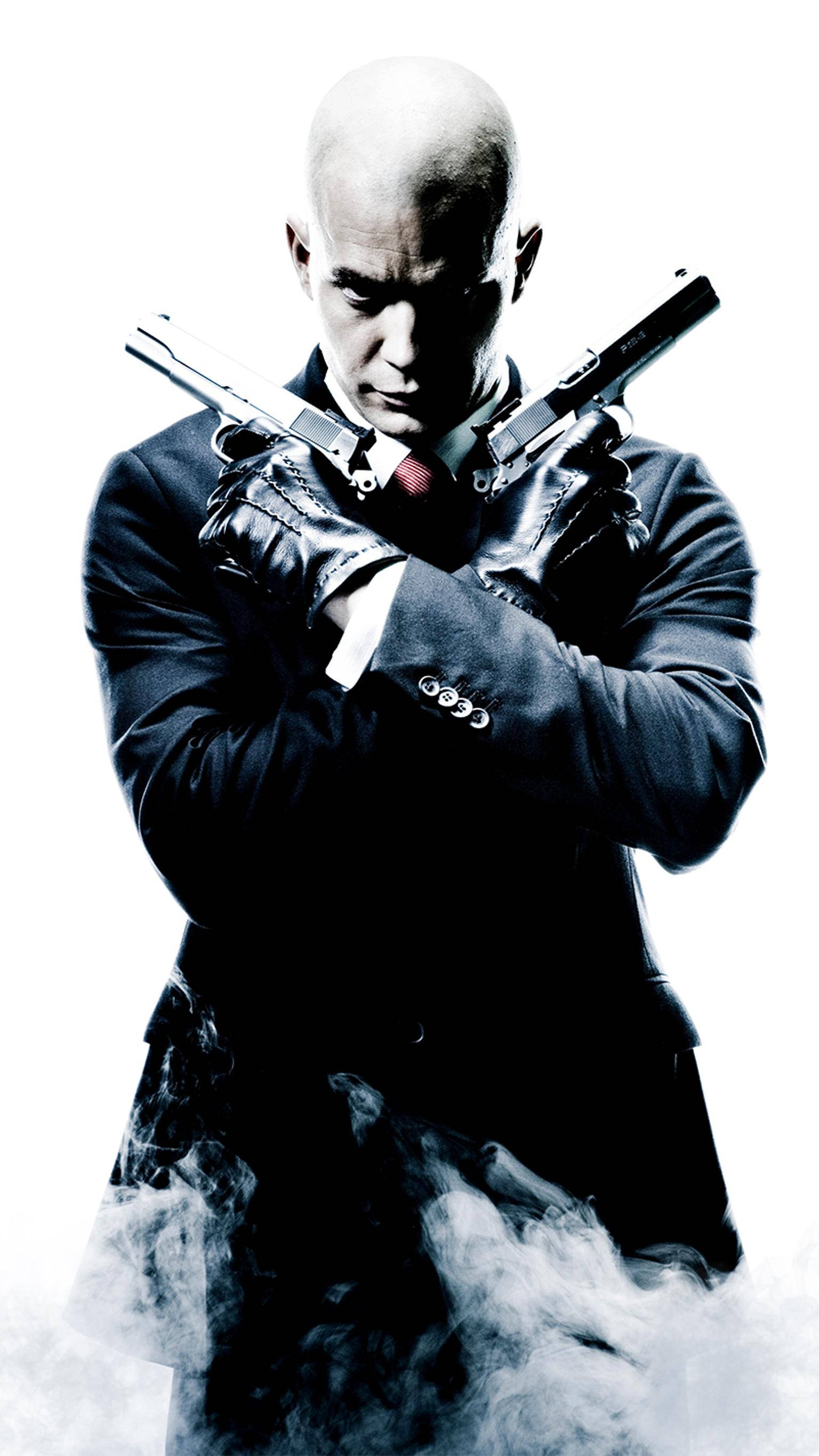 hitman iPhone 桌布 壁紙 — 一個光頭男子穿著深色西裝，在純白背景前將兩把手槍交叉放在胸前，腳邊有煙霧繚繞。