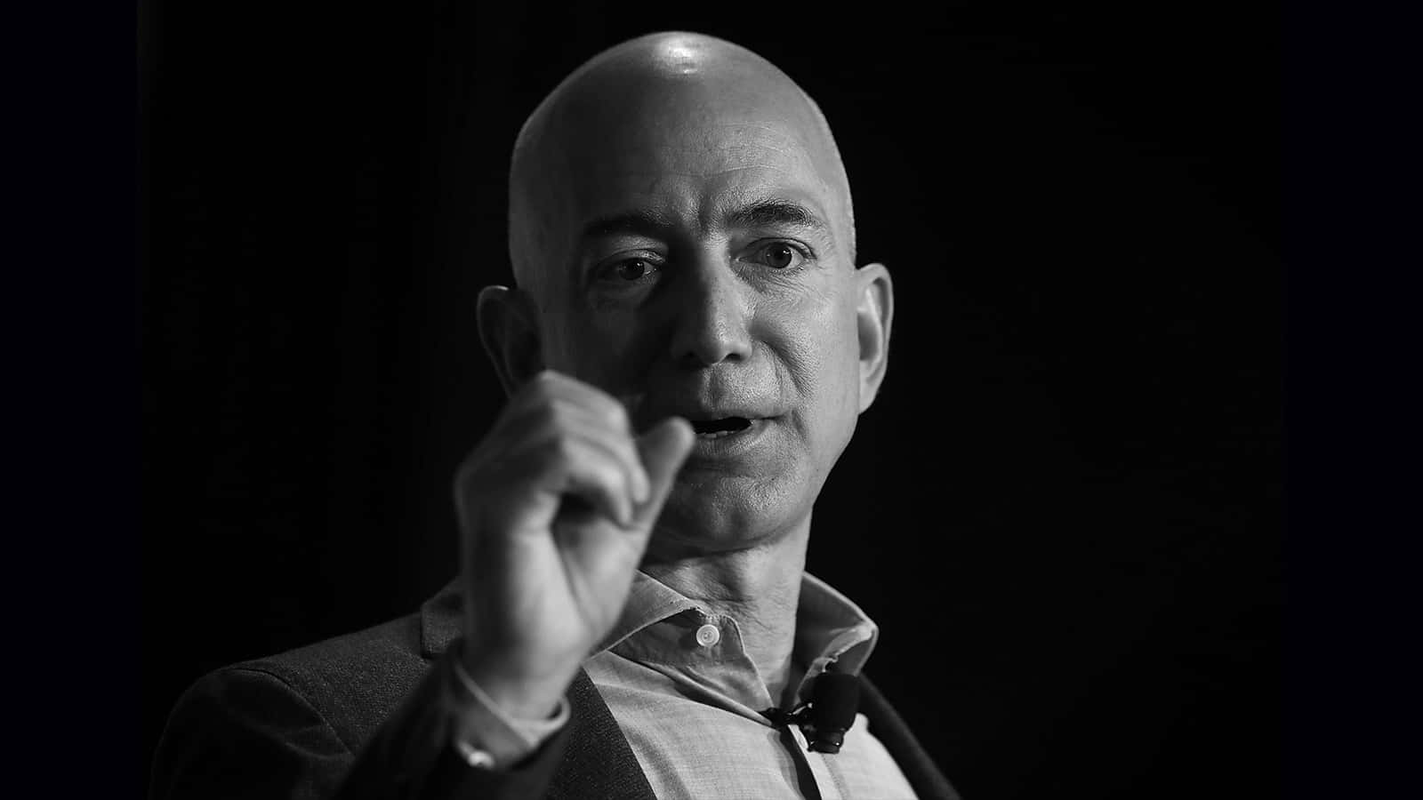 Jeff Bezos 桌布 壁紙 — 一個光頭男子穿著西裝，在深色背景下用右手做手勢的黑白肖像。