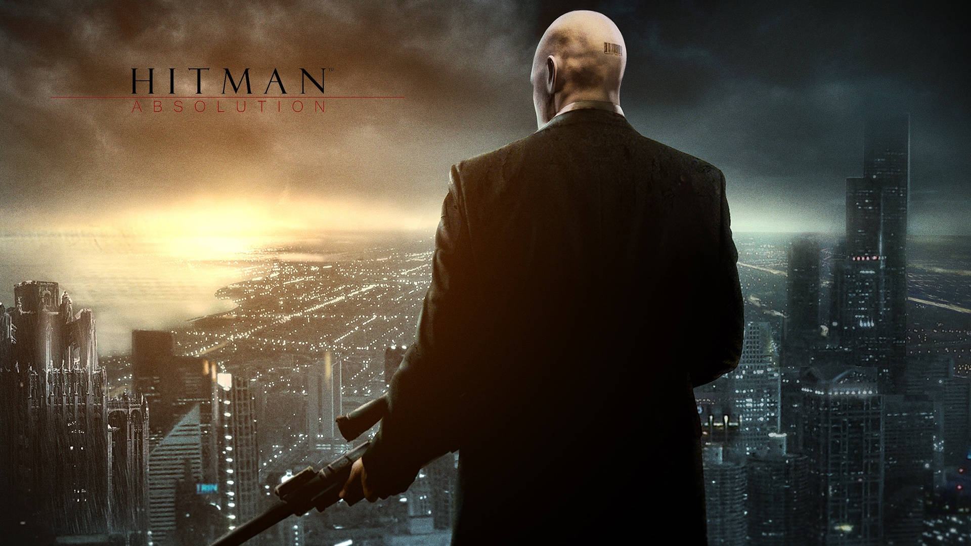 hitman absolution HD 桌布 壁紙 — 一個光頭男子穿著西裝，在黃昏時分俯瞰廣闊的城市天際線，手持一把消音手槍。