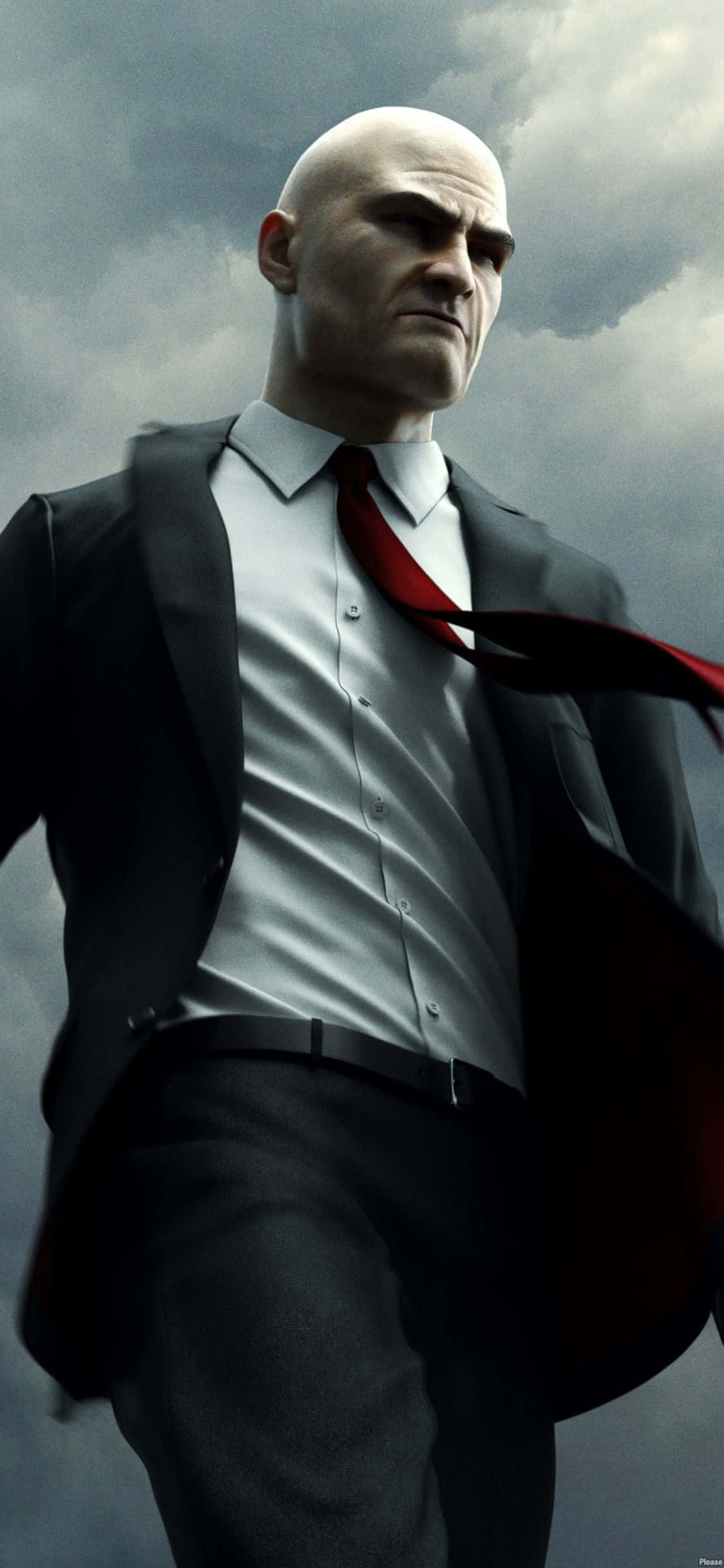 iPhone X Hitman Absolution 桌布 壁紙 — 一個光頭男子穿著黑色西裝和紅色領帶，在暴風雨的灰色天空下，表情嚴肅地站立。
