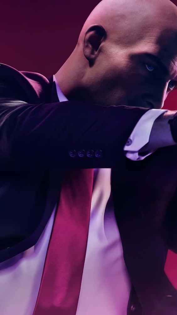Best Hitman 2 桌布 壁紙 — 一個光頭男子身穿深色西裝和紅色領帶，在戲劇性的紫色燈光下，以銳利的藍色眼睛向前傾。