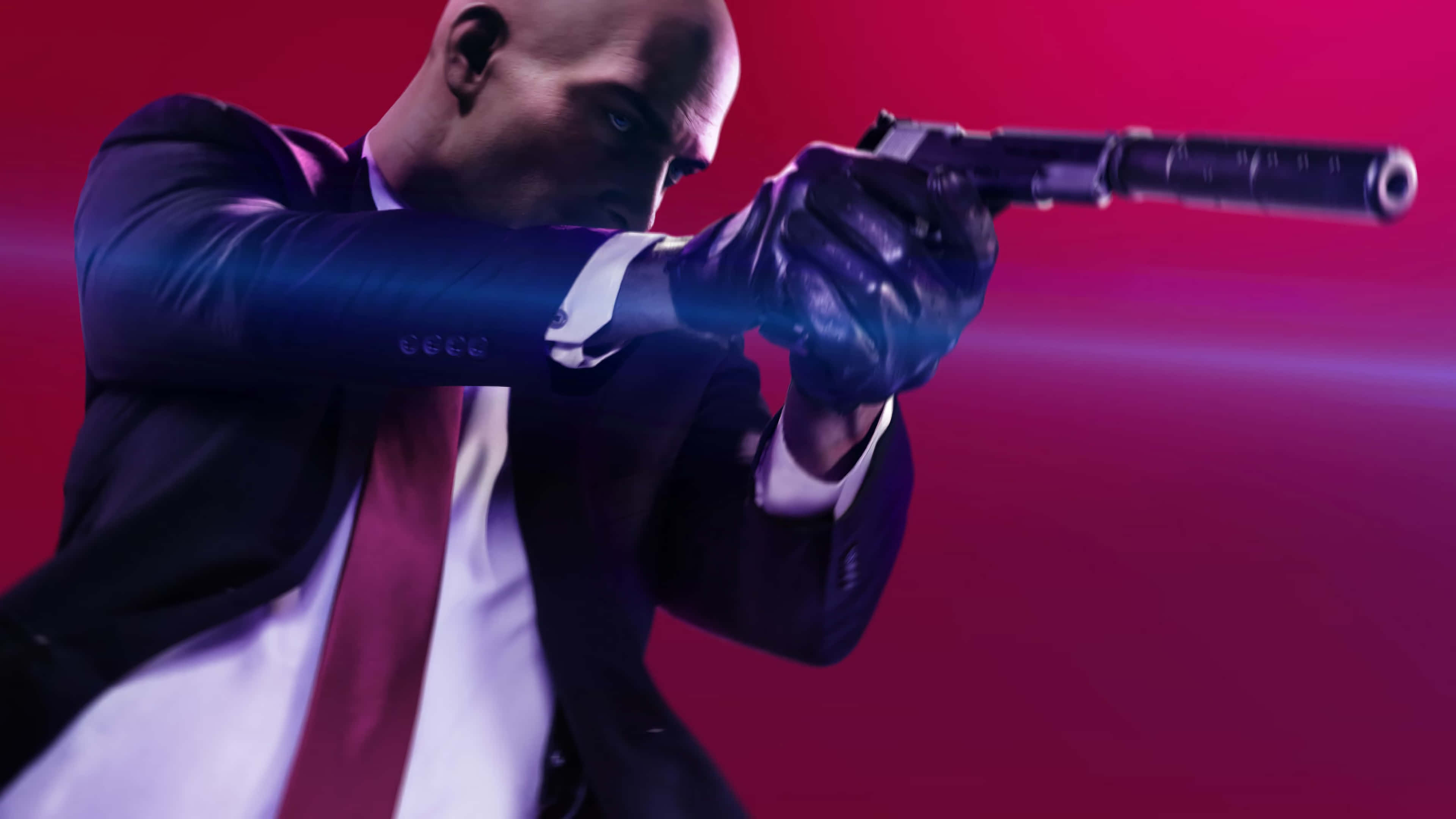 Hitman Desktop 桌布 壁紙 — 一個光頭男子身穿西裝，在充滿戲劇性燈光的鮮豔洋紅色背景下瞄準一把消音手槍。