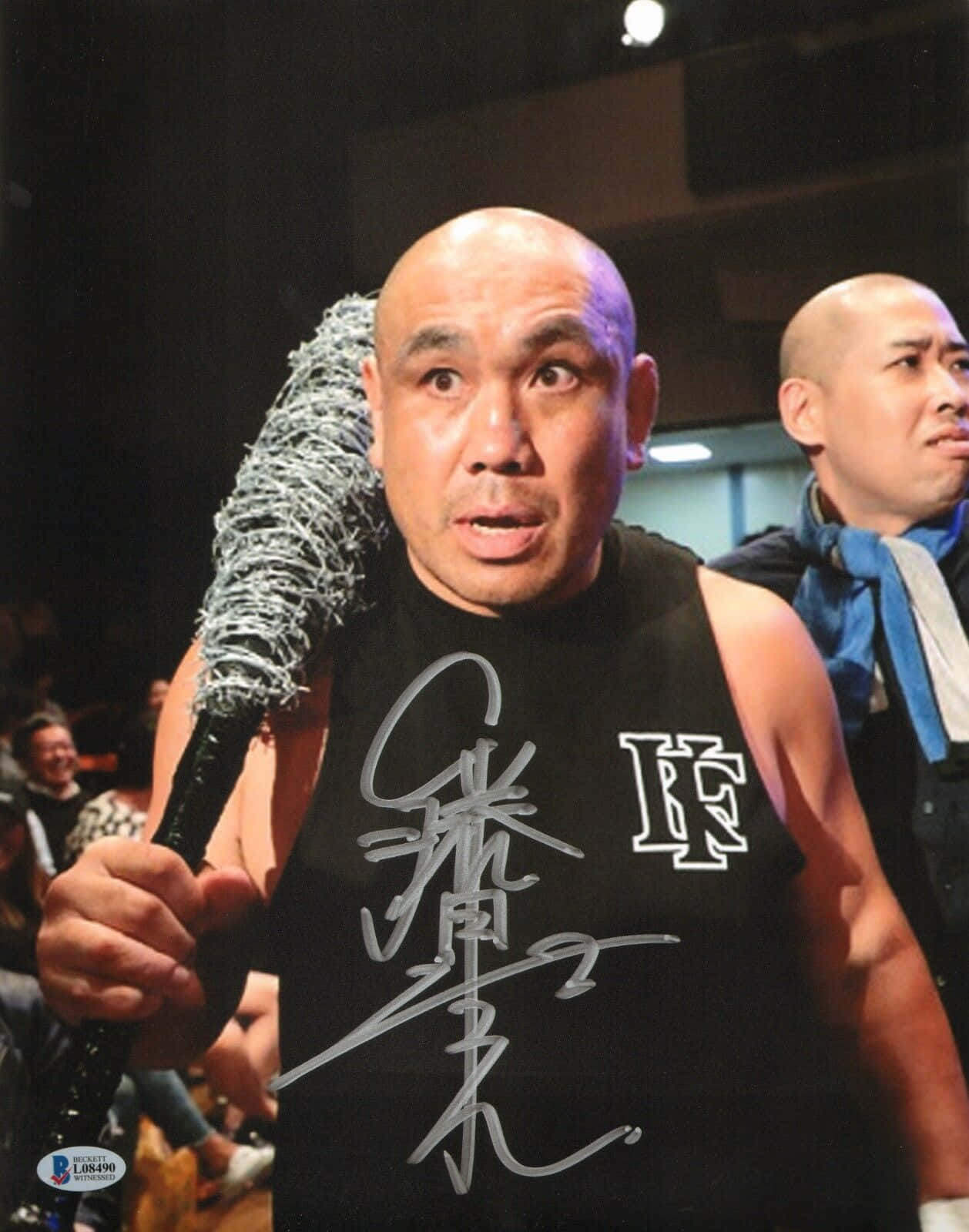 baseball bat 桌布 壁紙 — 一個光頭男子身穿黑色背心，在燈光昏暗的競技場中握著一根帶有鐵絲網的棒球棍，目光銳利地向前凝視。