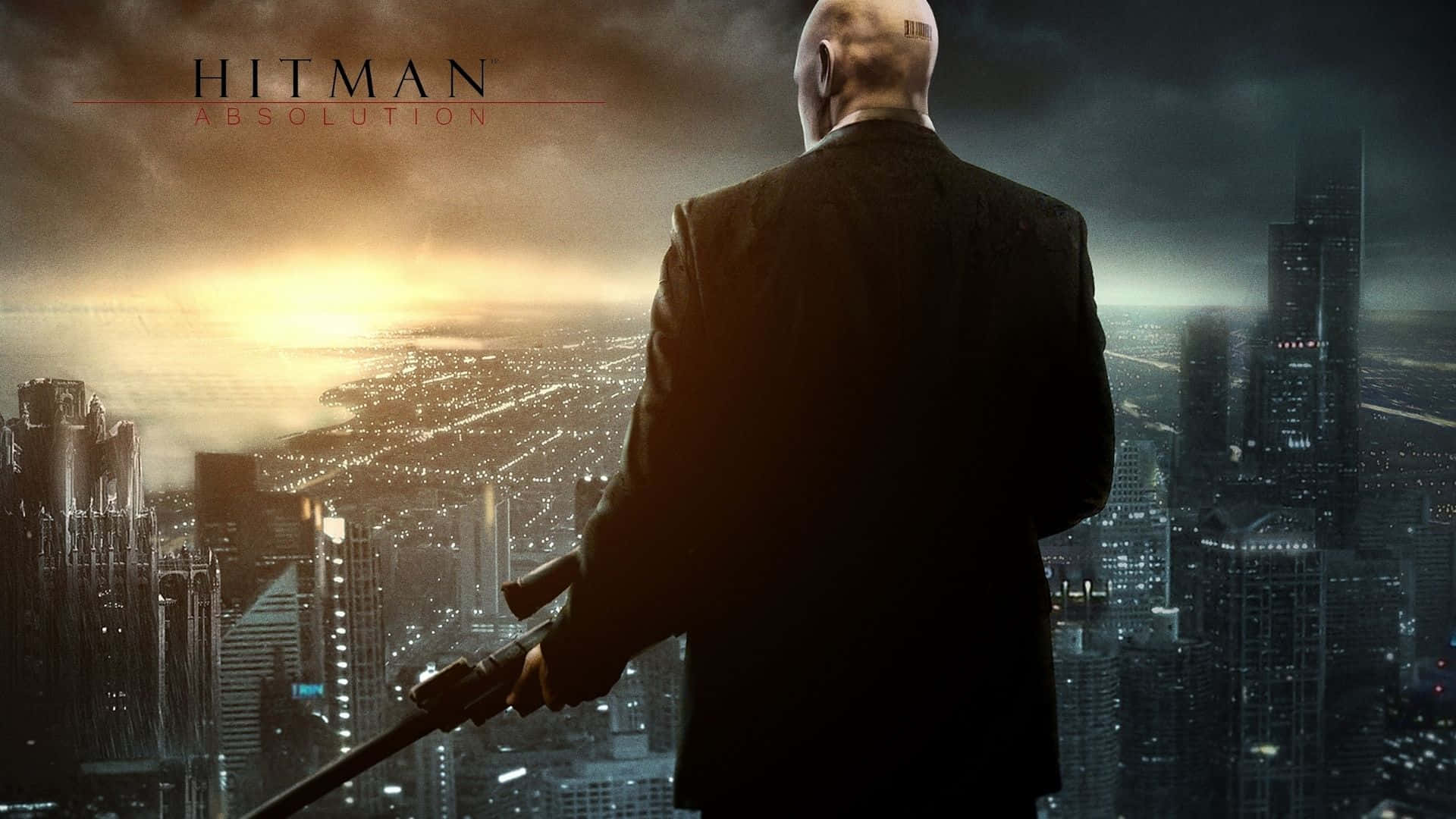1920x1080 Hitman Absolution 桌布 壁紙 — 一個光頭男子身穿黑色西裝，手持消音手槍，俯瞰著暮色中廣闊的城市景觀，天空金黃，烏雲密佈。