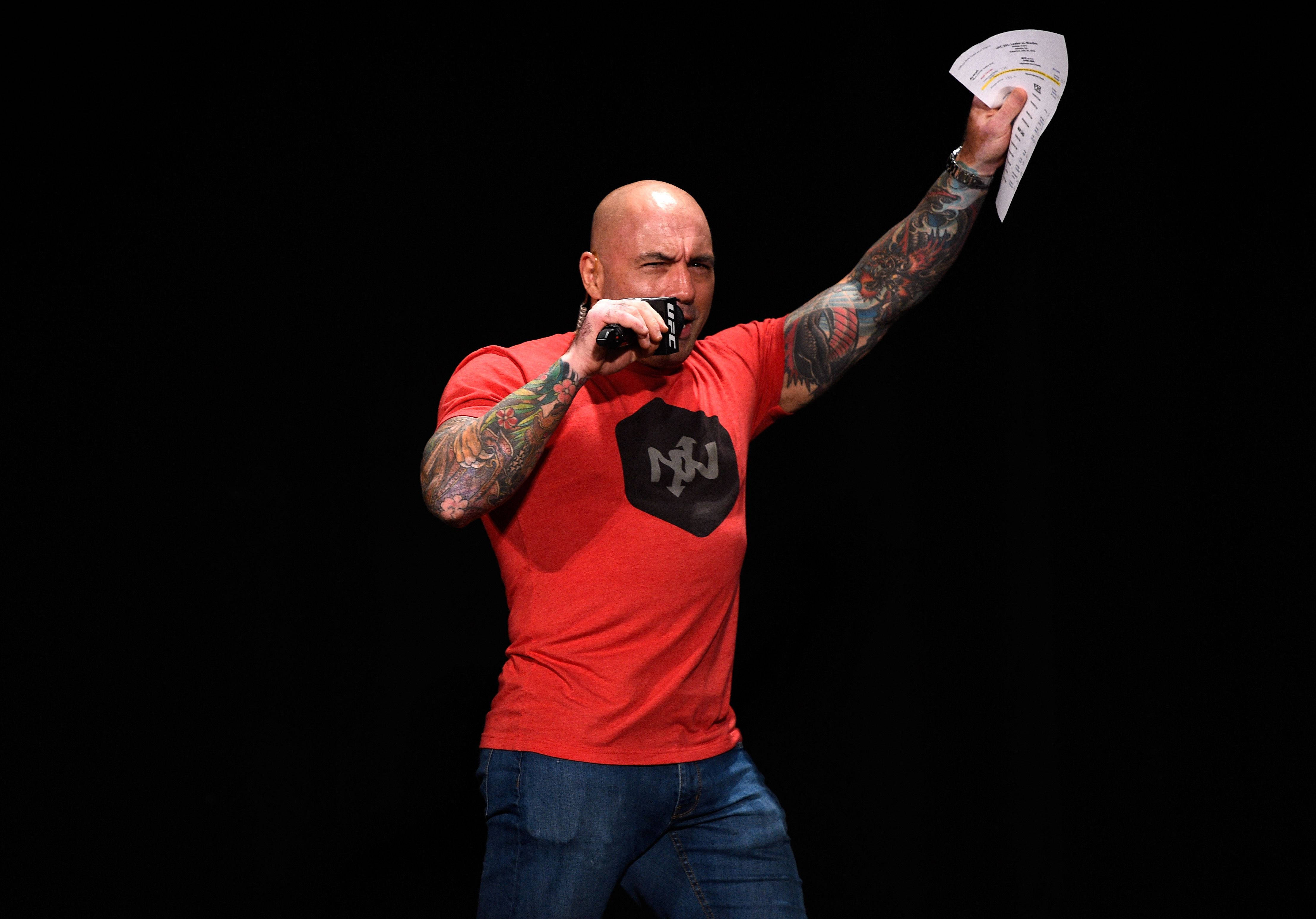 Tattoo 桌布 壁紙 — 一個光頭紋身男子在黑色背景前，一邊舉起紙張，一邊熱情地對著麥克風唱歌。