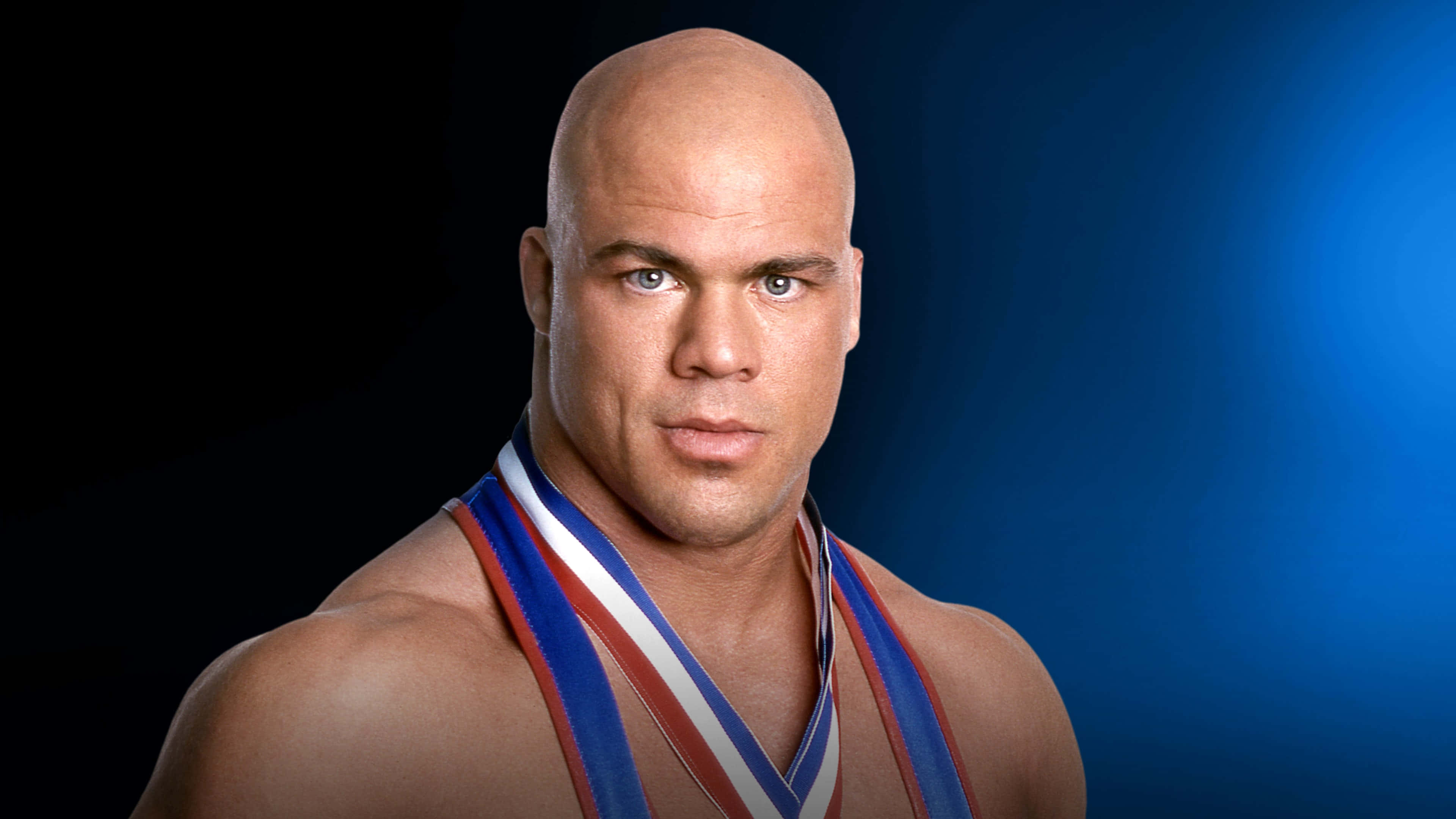 WWE 桌布 壁紙 — 一個光頭肌肉男，擁有強烈的藍色眼睛，在深藍色漸變背景前佩戴紅白藍三色獎章。