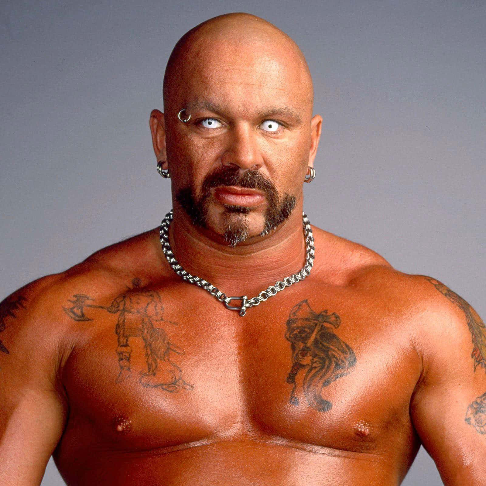 Perry Saturn 桌布 壁紙 — 一個光頭肌肉男，身上有刺青和穿孔，在純灰色背景前凝視著。