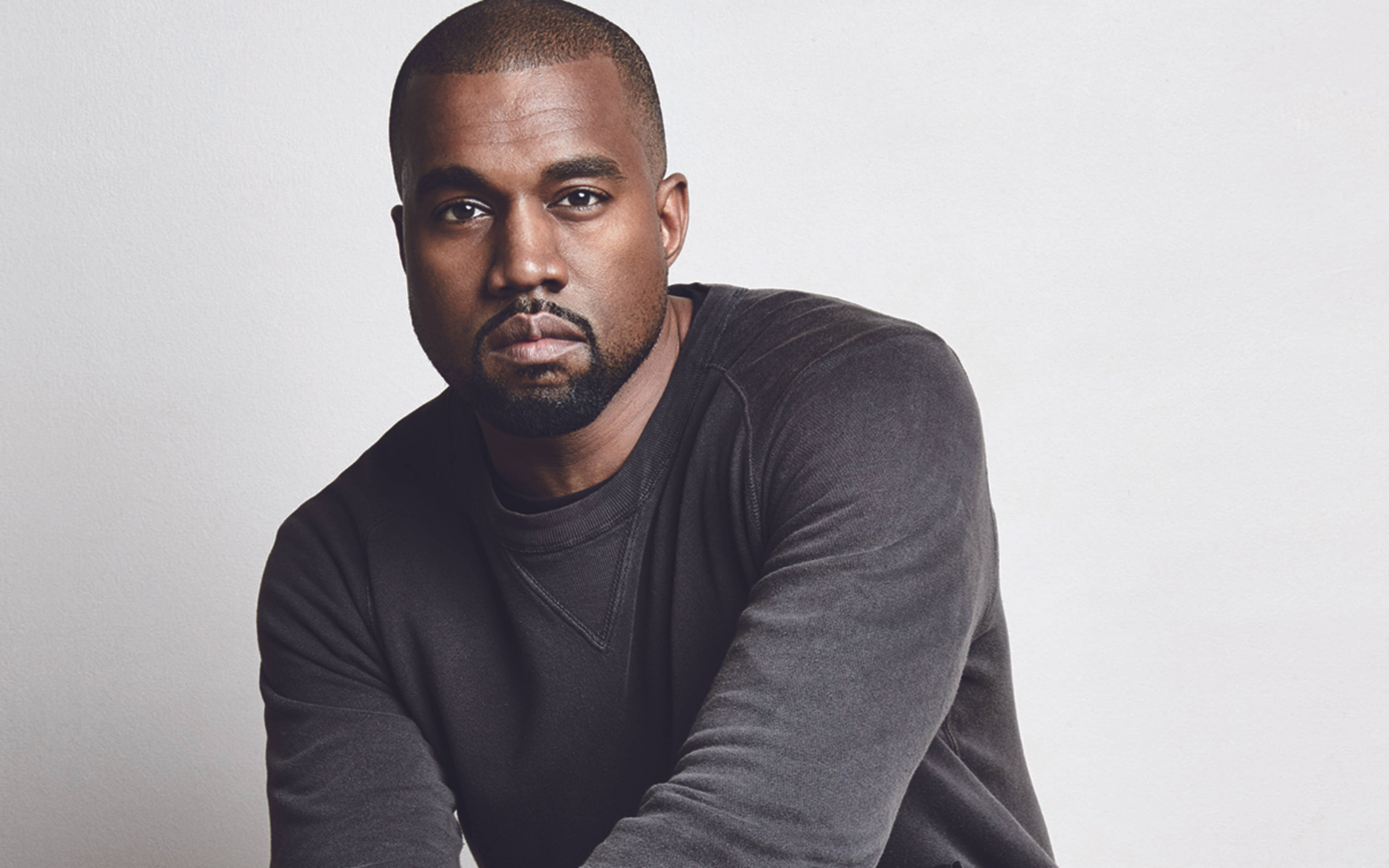Kanye West Ye 桌布 壁紙 — 一個光頭鬍鬚男，身穿深灰色毛衣，背景為純白色。