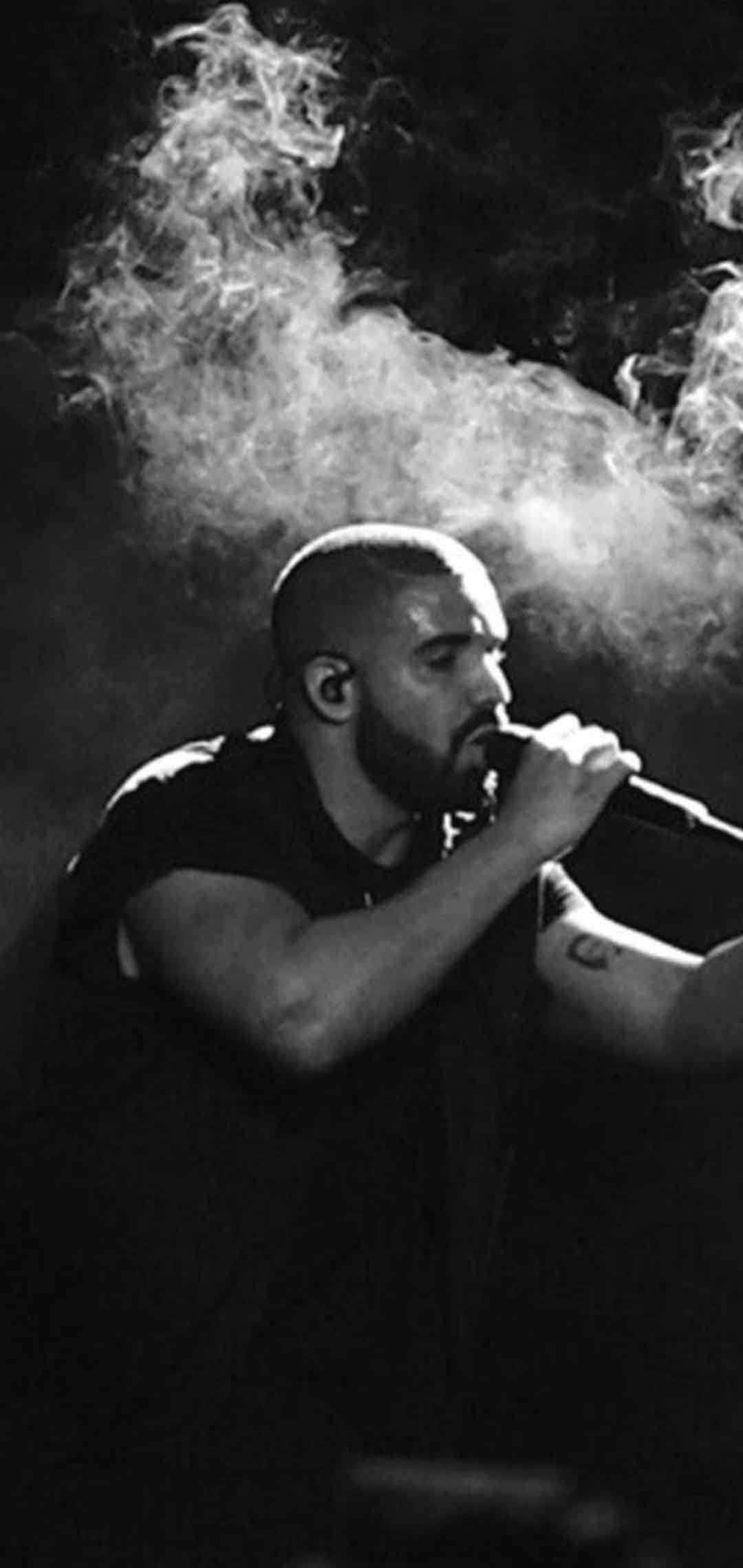 Drake 桌布 壁紙 — 一個光頭鬍鬚男對著麥克風唱歌，身後煙霧翻騰的黑白照片。