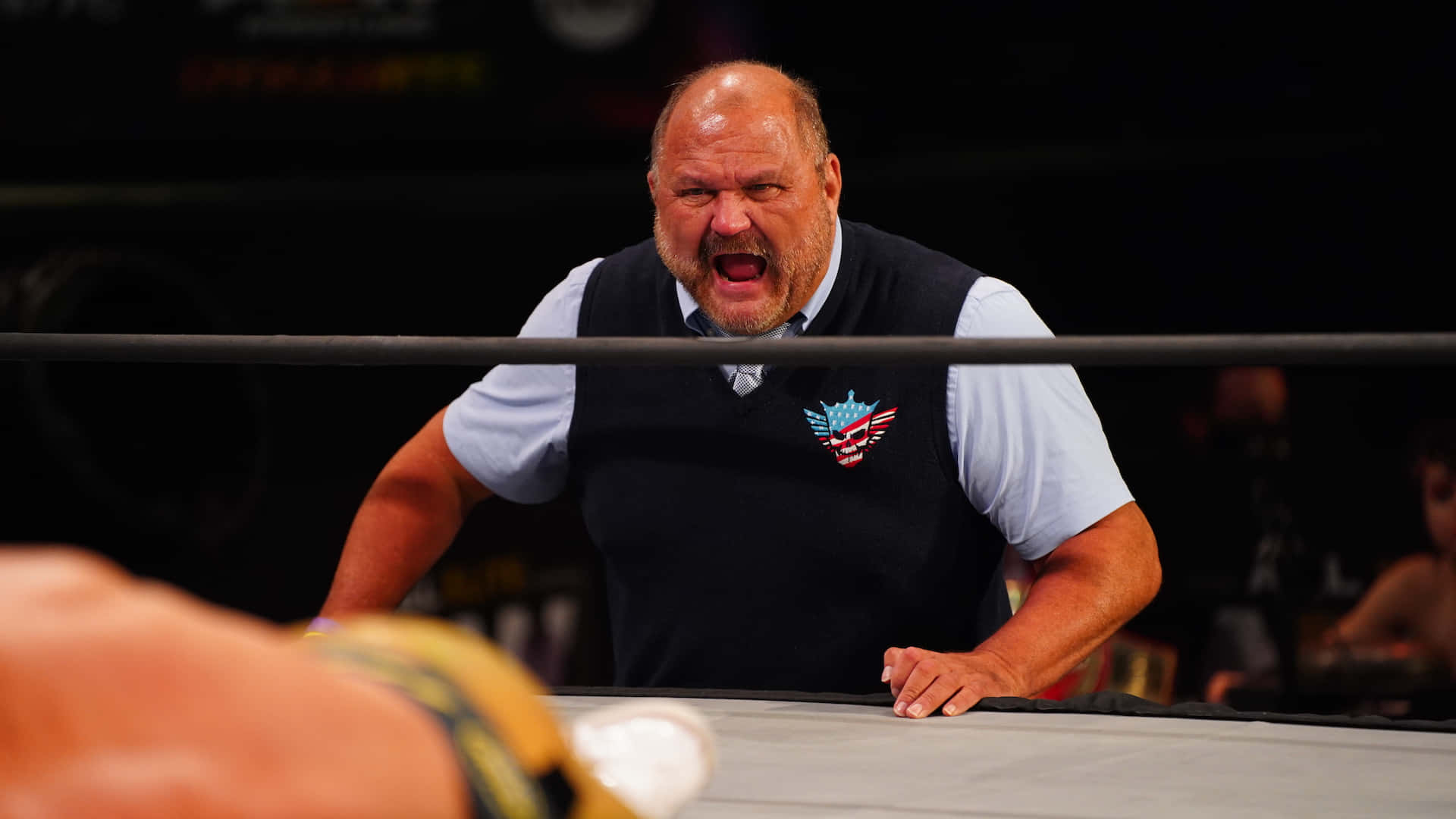 WWE 桌布 壁紙 — 一個光頭鬍鬚男從摔角擂台繩索後面，向擂台內的對手激烈尖叫。
